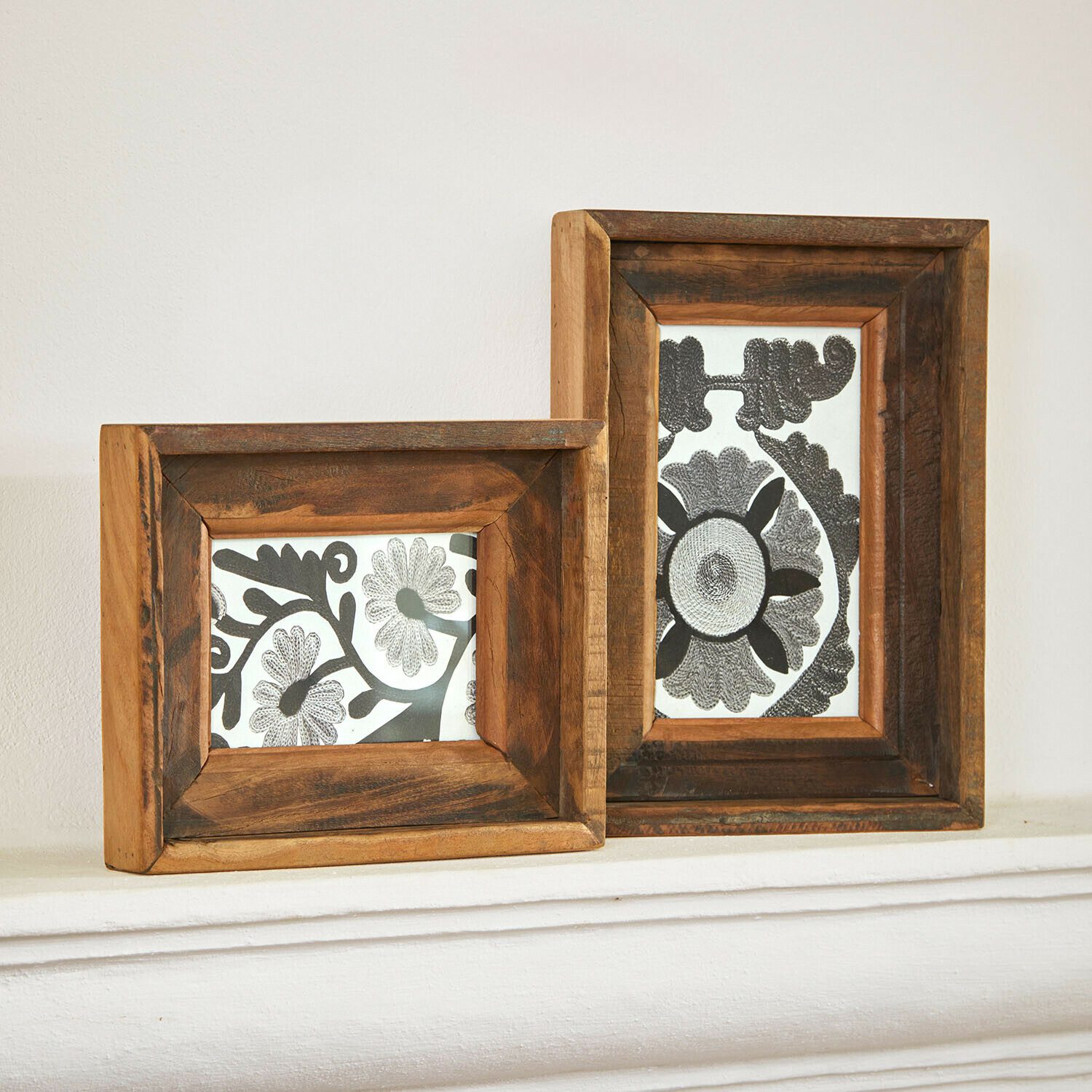Twee rustieke fotolijsten van natuurlijk bruin hout met zwart-witte bloemmotieven binnenin