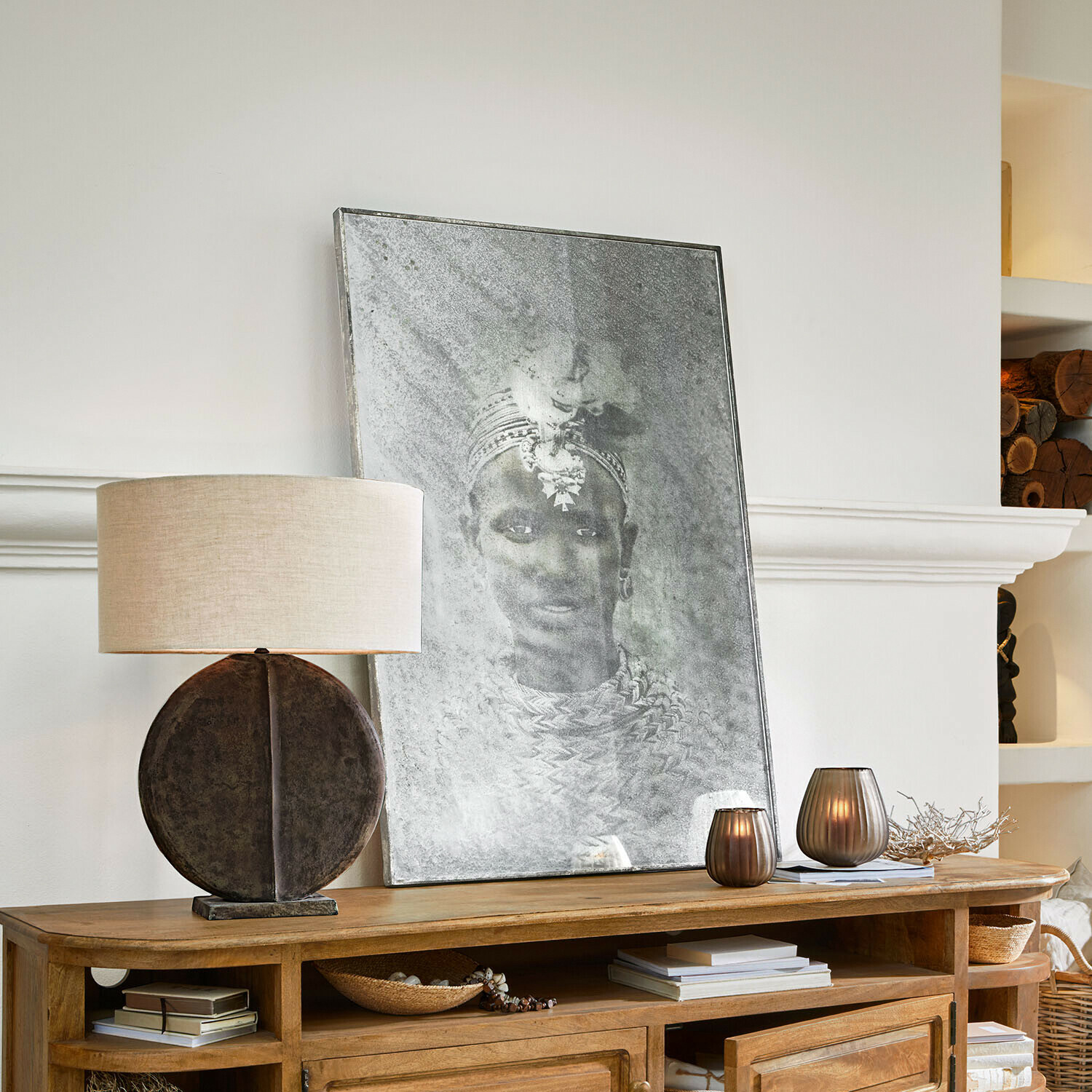 Decoratieve lamp met ronde voet en kap op houten dressoir met schilderij en kaarsen