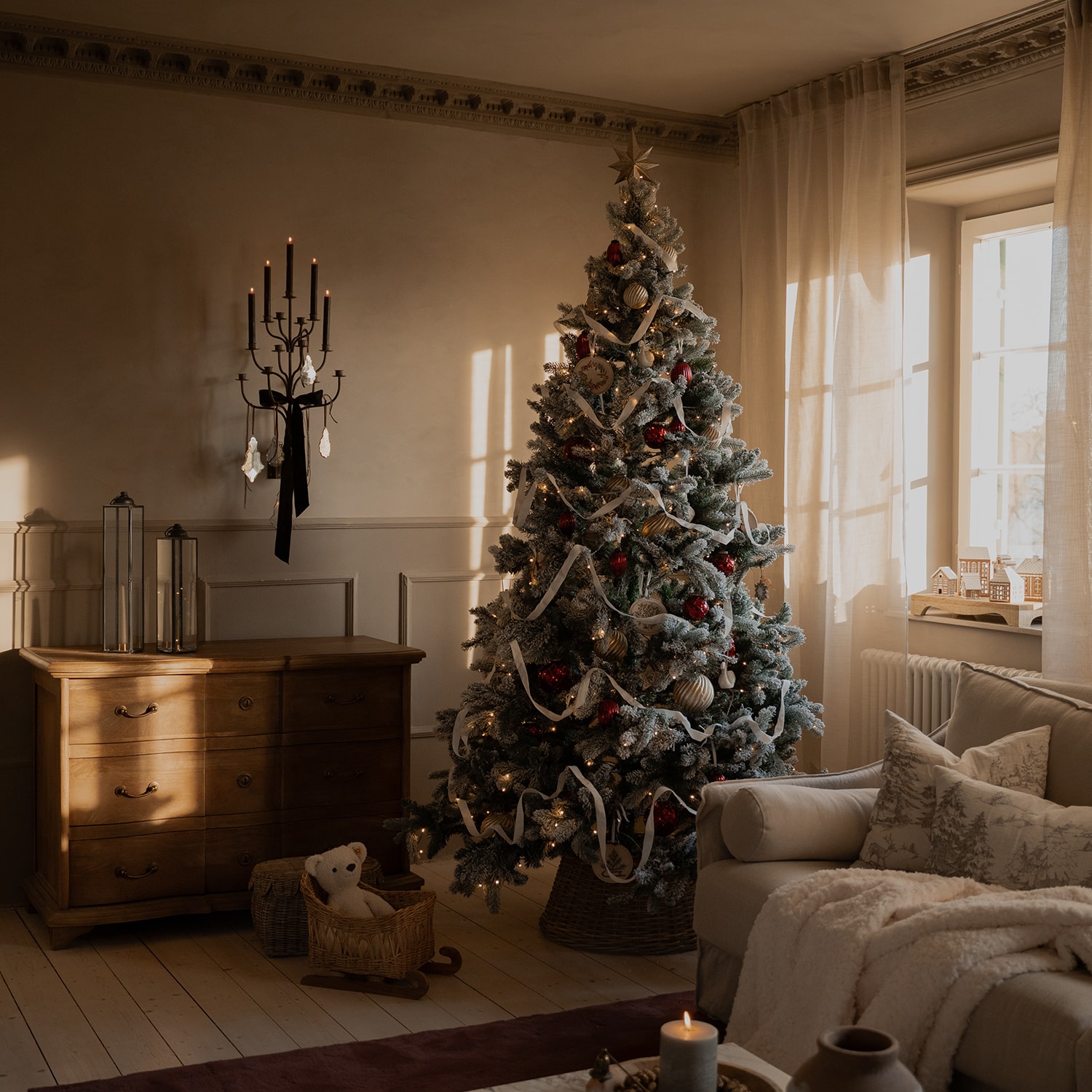 Gezellige woonkamer met besneeuwde kerstboom versierd met rode en gouden ballen en witte lint