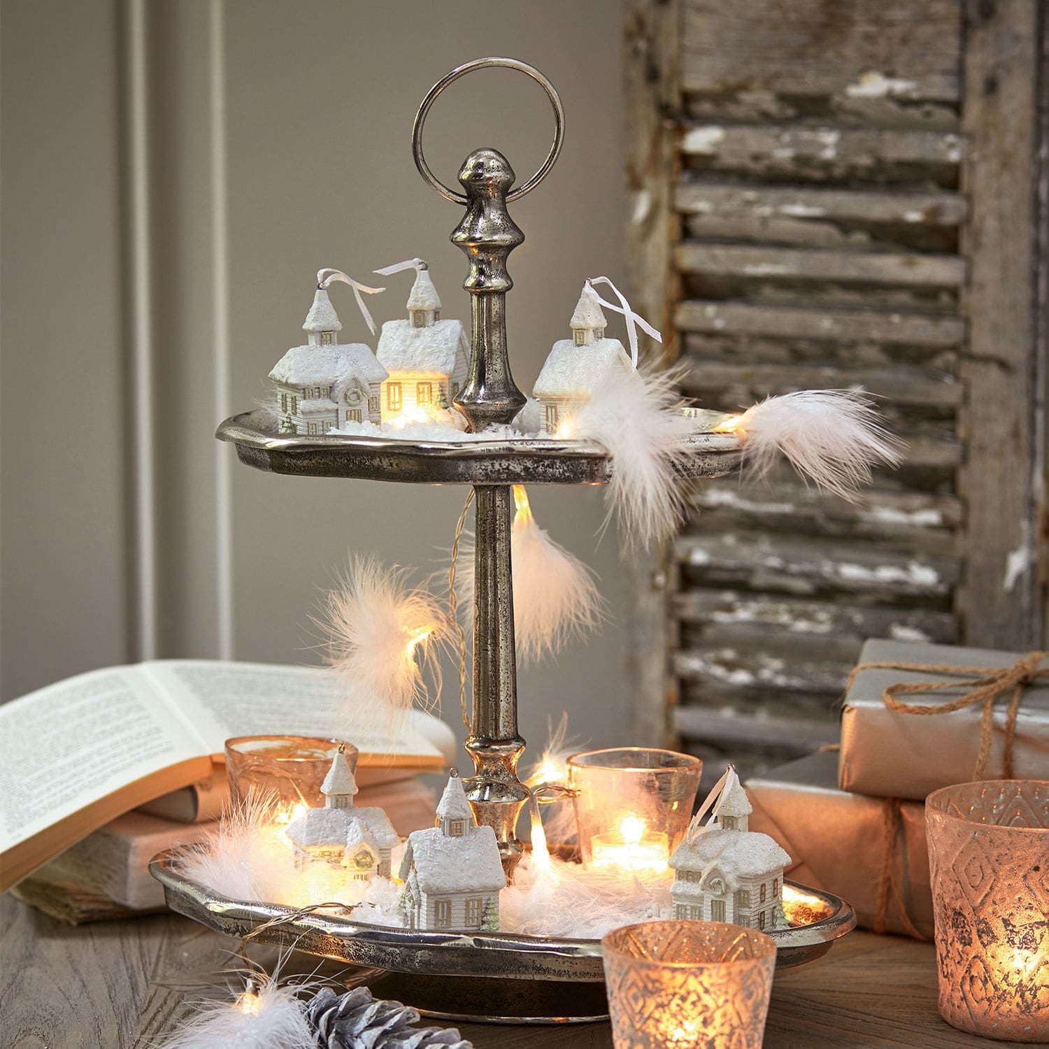 Twee verdiepingen metalen etagère met witte huisdecoraties en LED-lichtjes voor kerstversiering