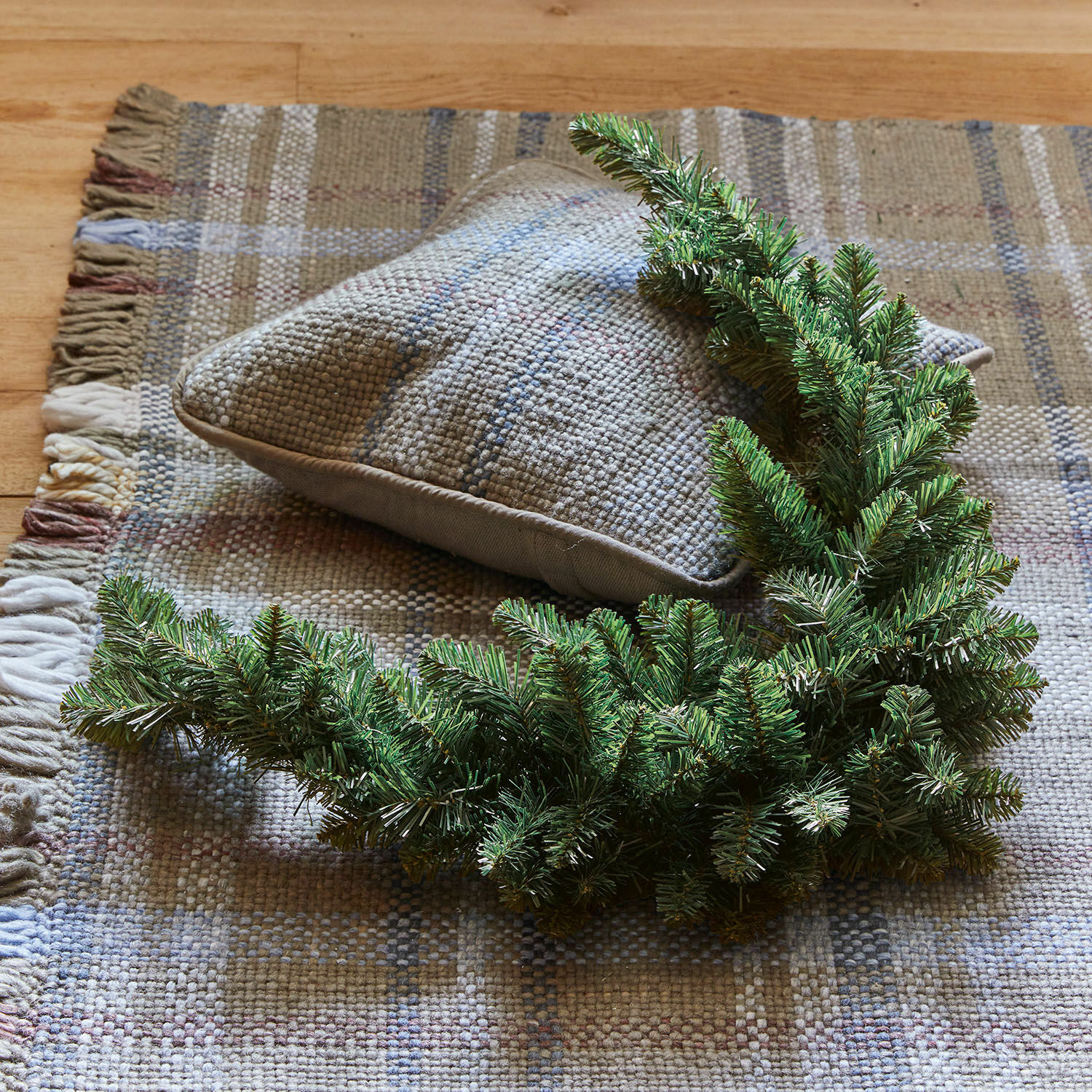 Guirlande Melis Groene decoratieve krans van dennentakken op beige geweven tapijt met kussen