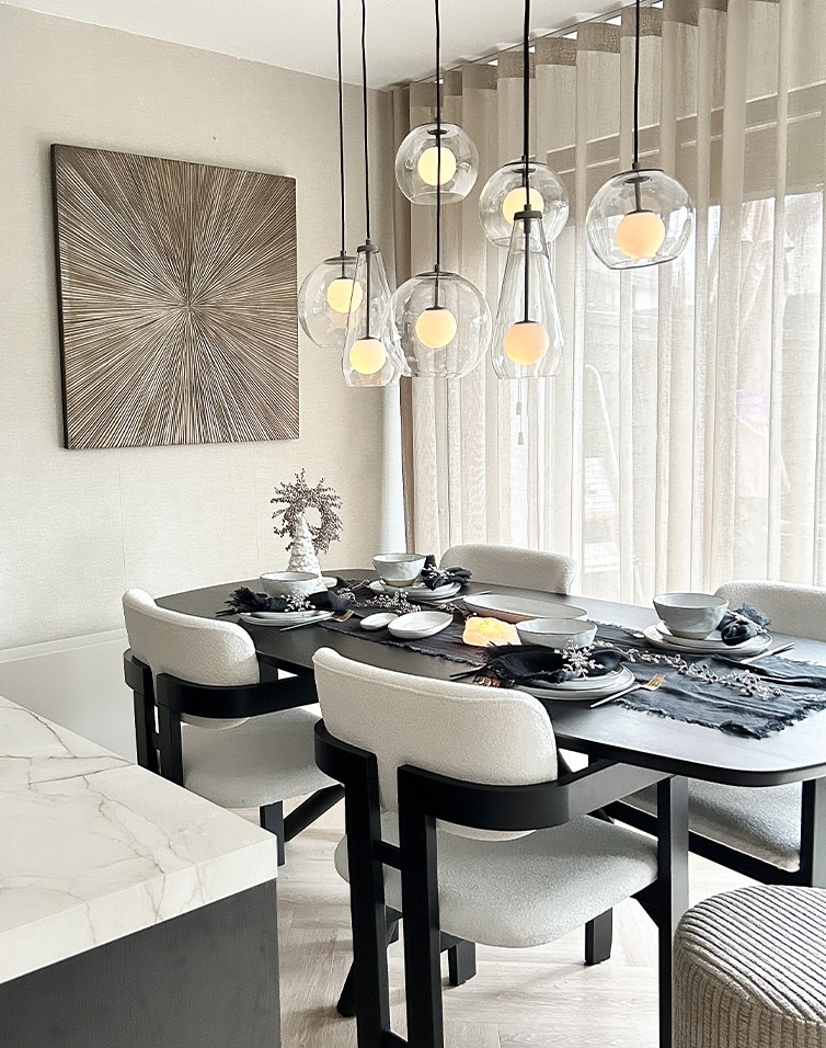 Moderne zwarte eettafel met witte stoelen en hangende glazen lampen in lichte ruimte