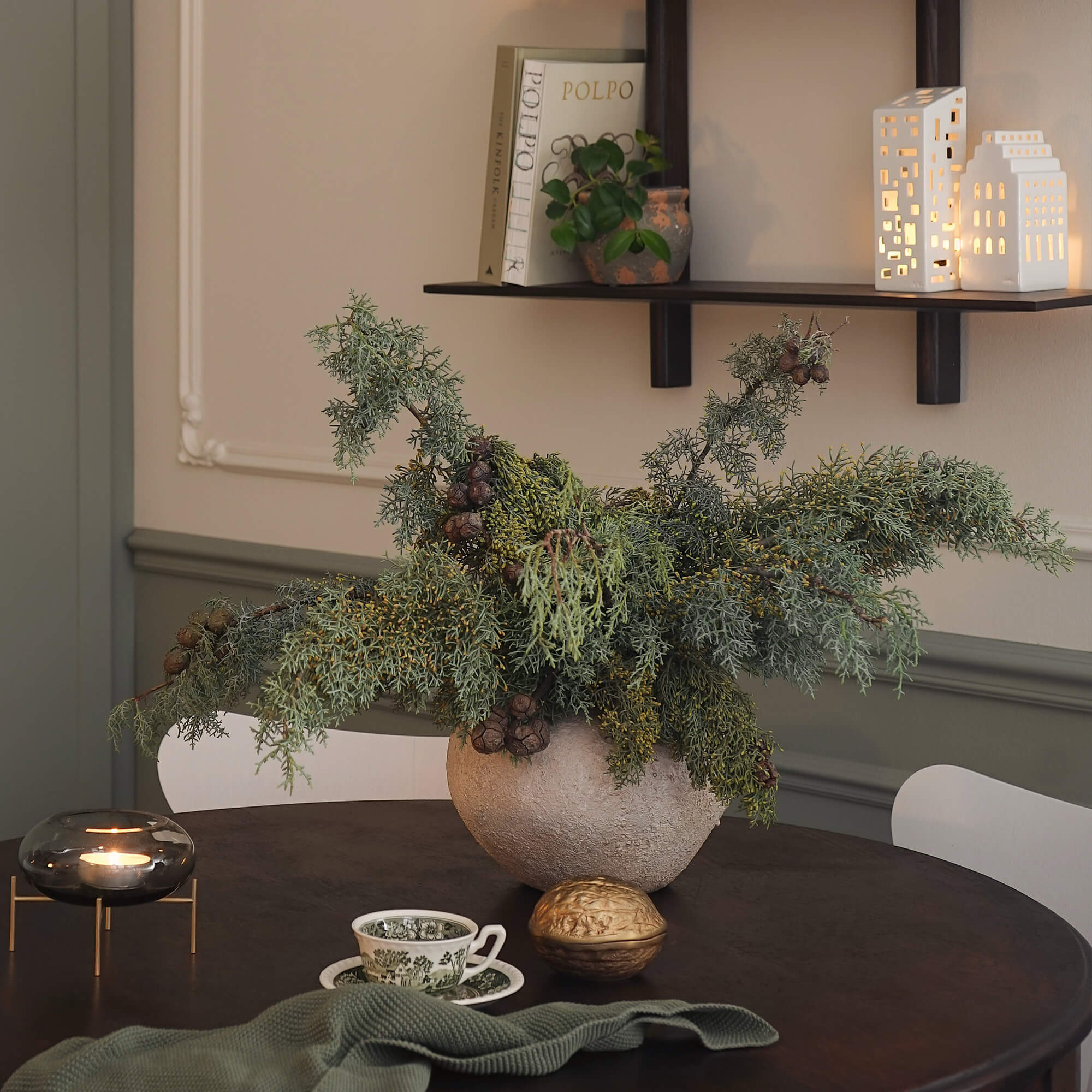 Decoratieve compositie van groene takken in stenen pot op donkere tafel in woonkamer
