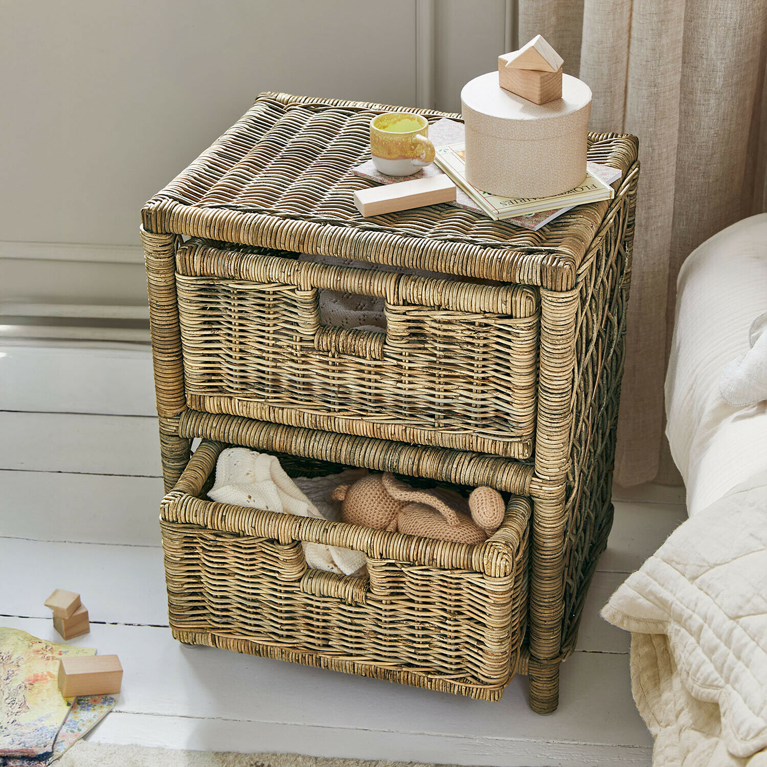 Twee-laags kast van natuurlijk riet met decoraties bovenop en zachte stoffen binnenin