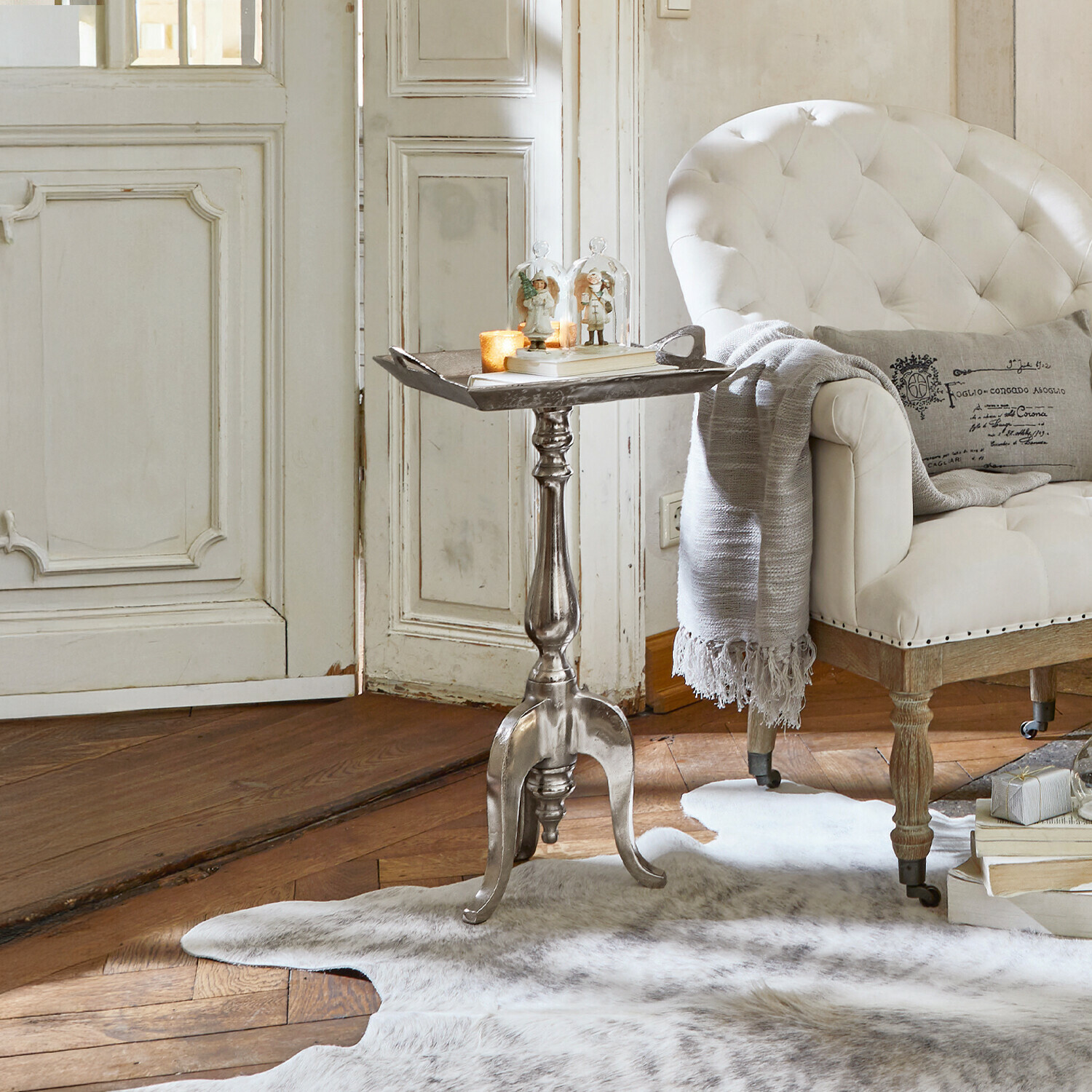 Bijzettafel Melvin Zilverkleurige metalen bijzettafel met decoraties, geschikt voor woonkamer met witte fauteuil en bontkleed
