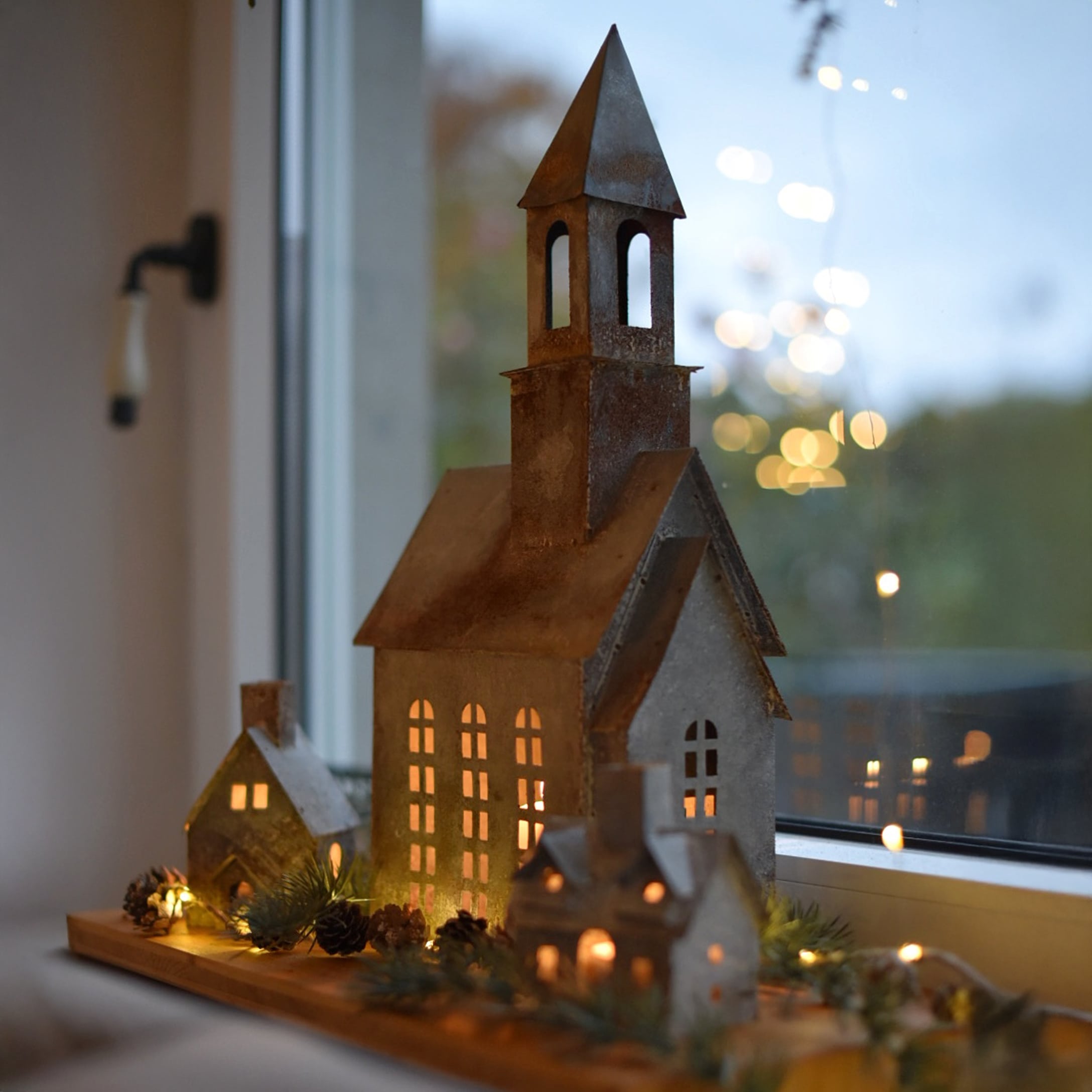Decoratieve set metalen huisjes en kerk met LED-verlichting op houten plank