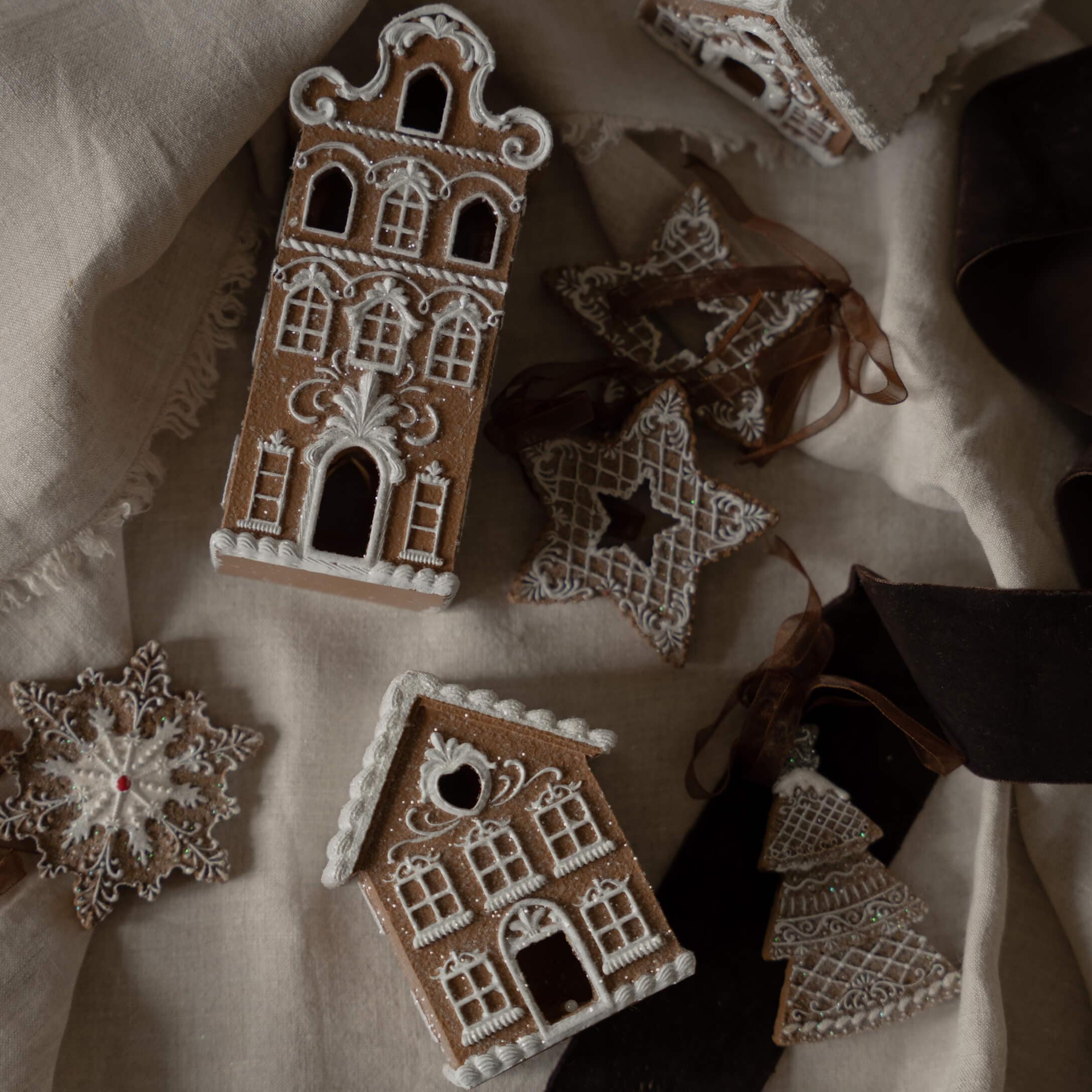 Gemberkoekhuisjes en sterren met witte glazuur op linnen stof, kerstdecoraties