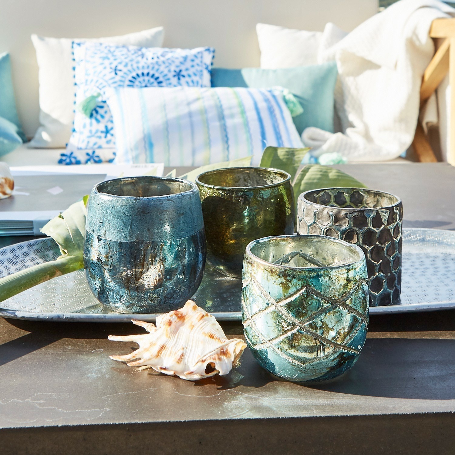 Set van vier glazen theelichthouders in blauw- en groentinten op metalen dienblad met schelp