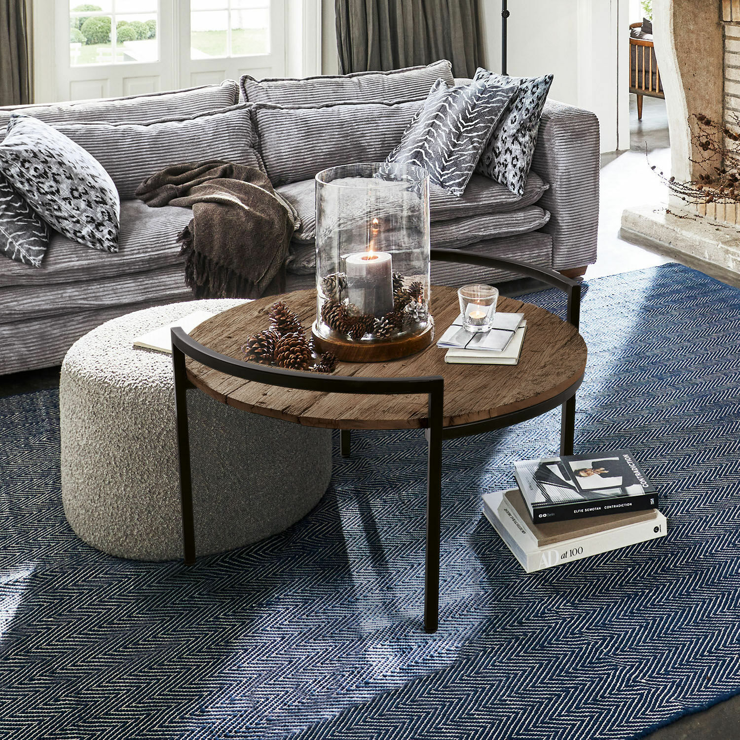 Ronde salontafel met houten blad en metalen frame op blauwe vloerkleed in woonkamer