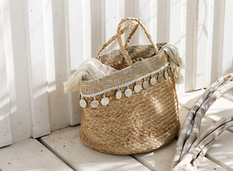 Boho mand van gevlochten natuurlijk materiaal met decoratieve munten en lichte sjaal, interieurdecoratie.