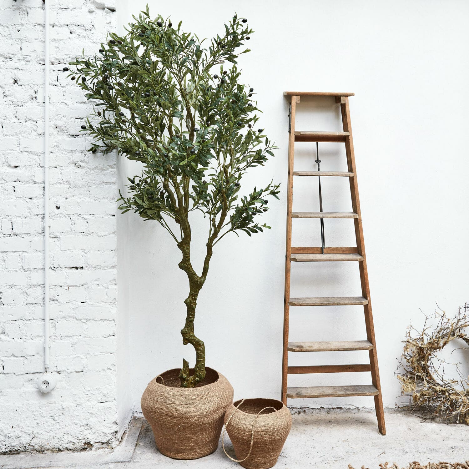 Sierpotplant Dambly Twee bruine jute plantenpotten naast een houten ladder tegen een witte muur