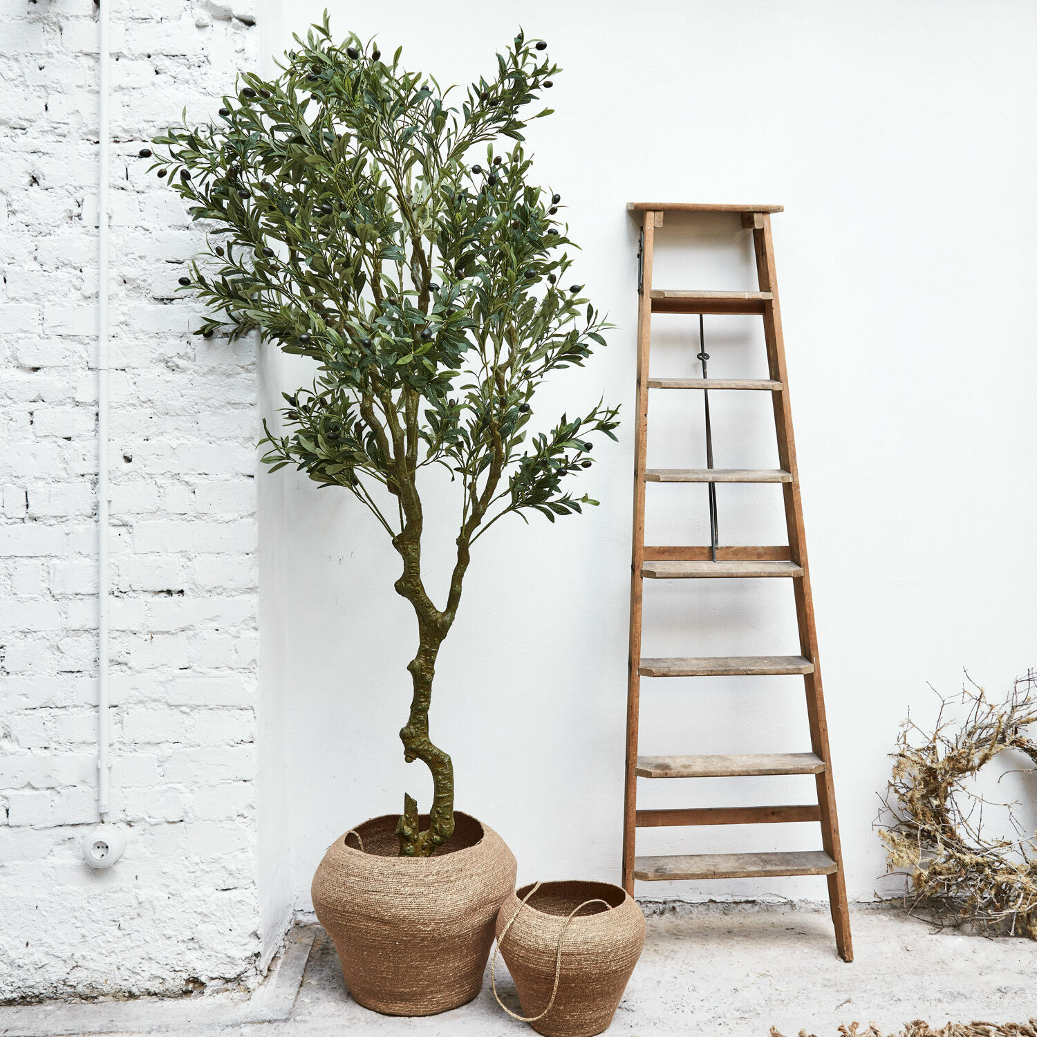 Sierpotplant Dambly Twee bruine jute plantenpotten naast een houten ladder tegen een witte muur