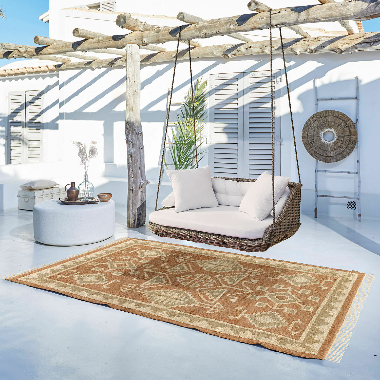 Beige en bruine vloerkleed met geometrisch patroon op lichte veranda met rotan schommel