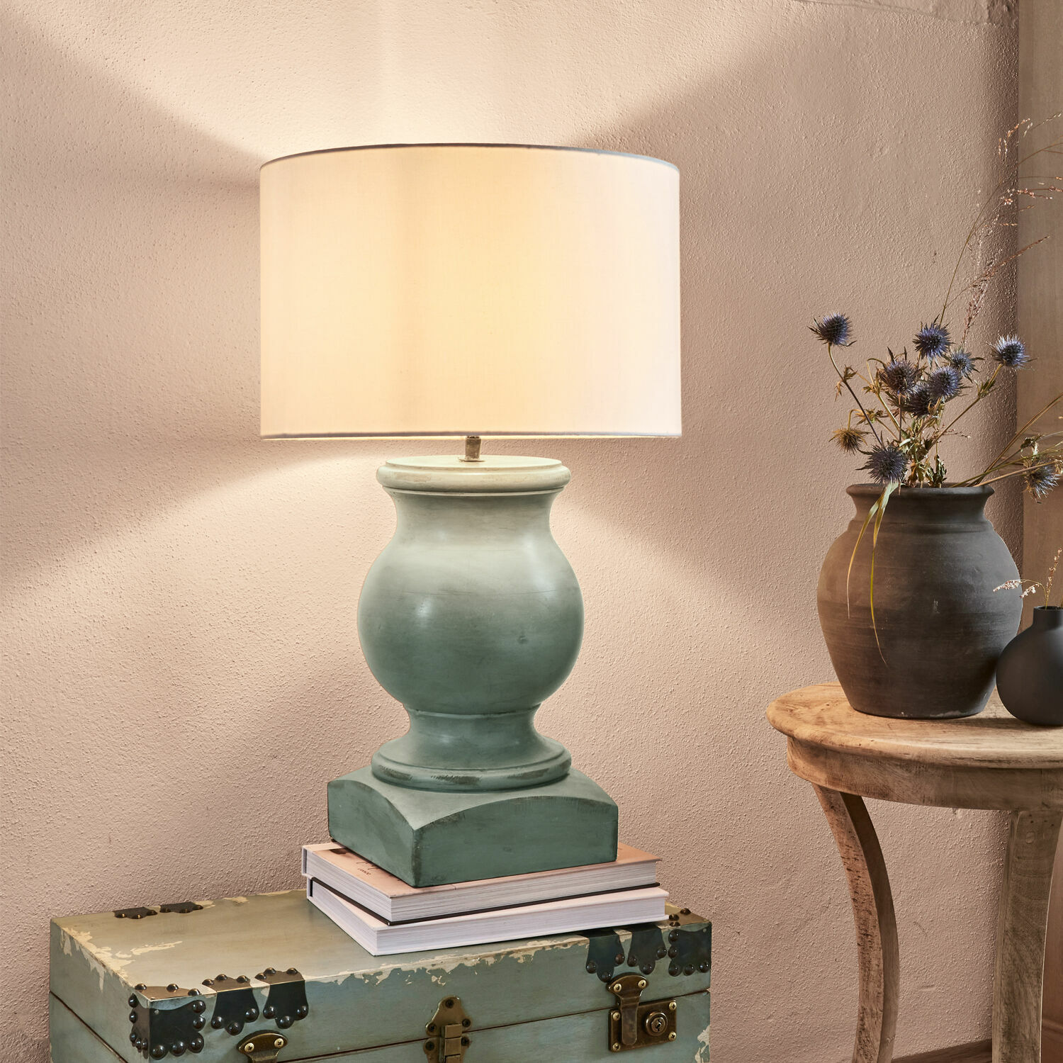 Tafellamp Todd Tafellamp van groene keramiek met beige kap op een oude kist, interieurdecoratie