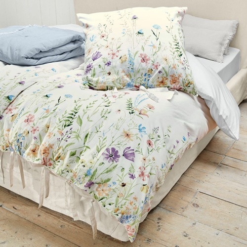 Katoenen beddengoed met kleurrijk bloemenpatroon op lichte achtergrond, zacht en decoratief voor slaapkamer