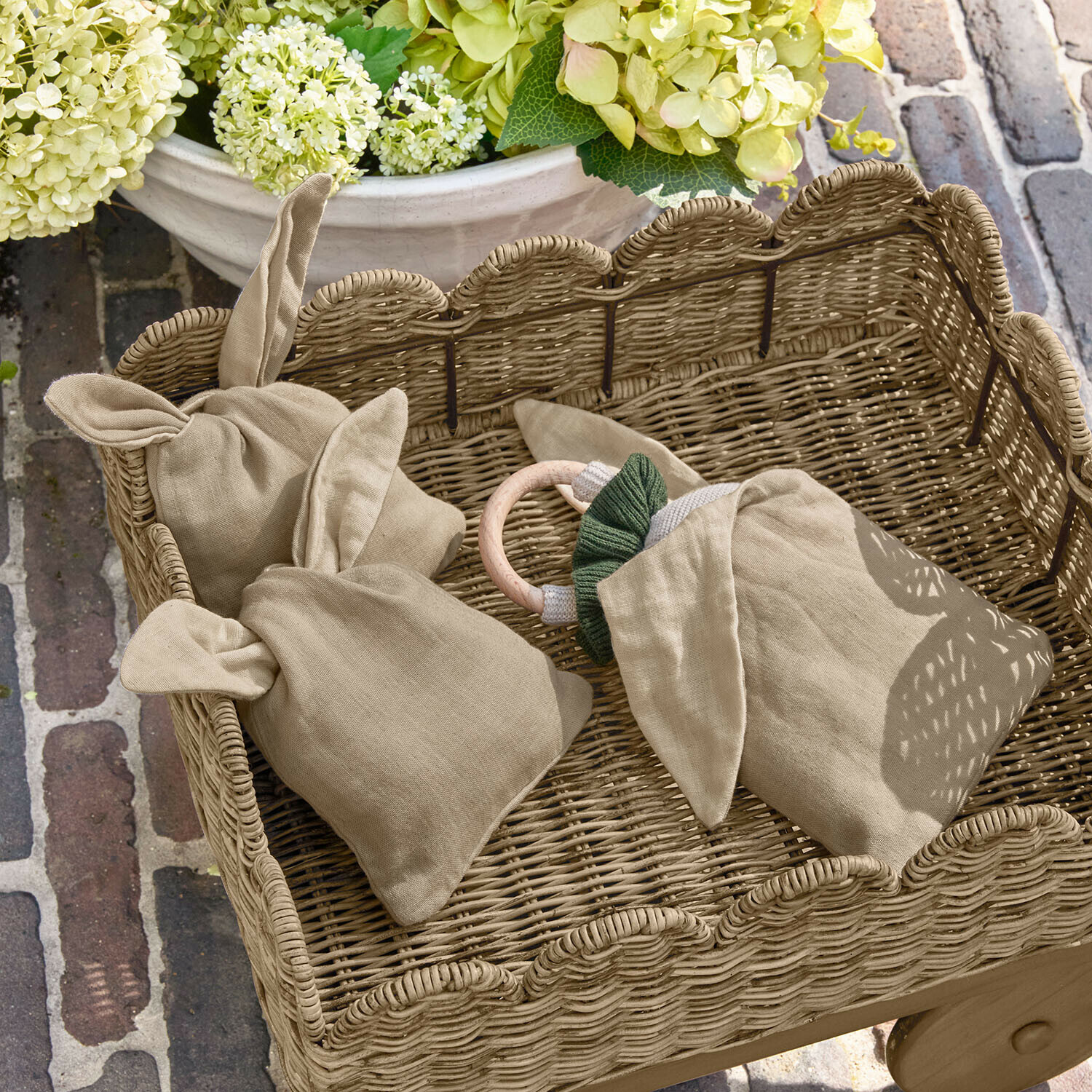 Beige linnen zak met oren in een rieten mand, bloemen en bakstenen vloer op de achtergrond