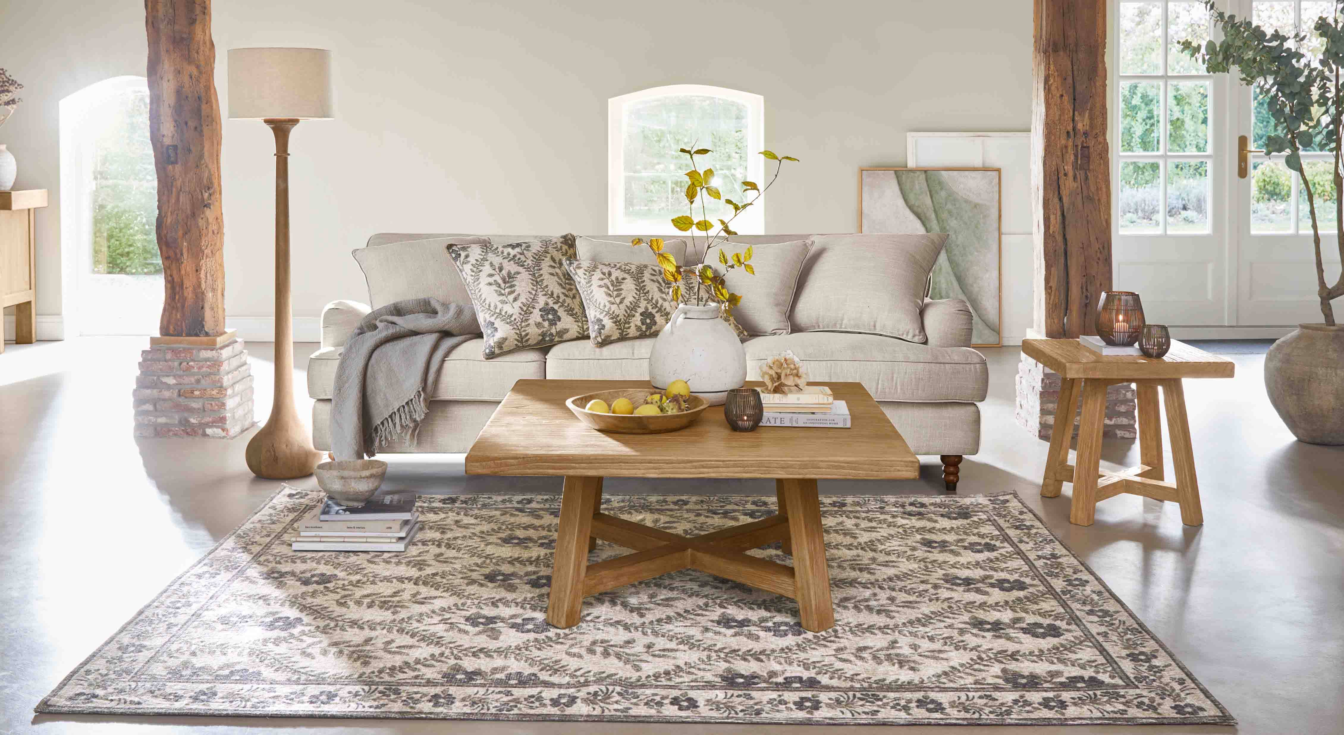 Gezellige woonkamer met beige bank, houten salontafel en decoratief vloerkleed met bloemenpatroon