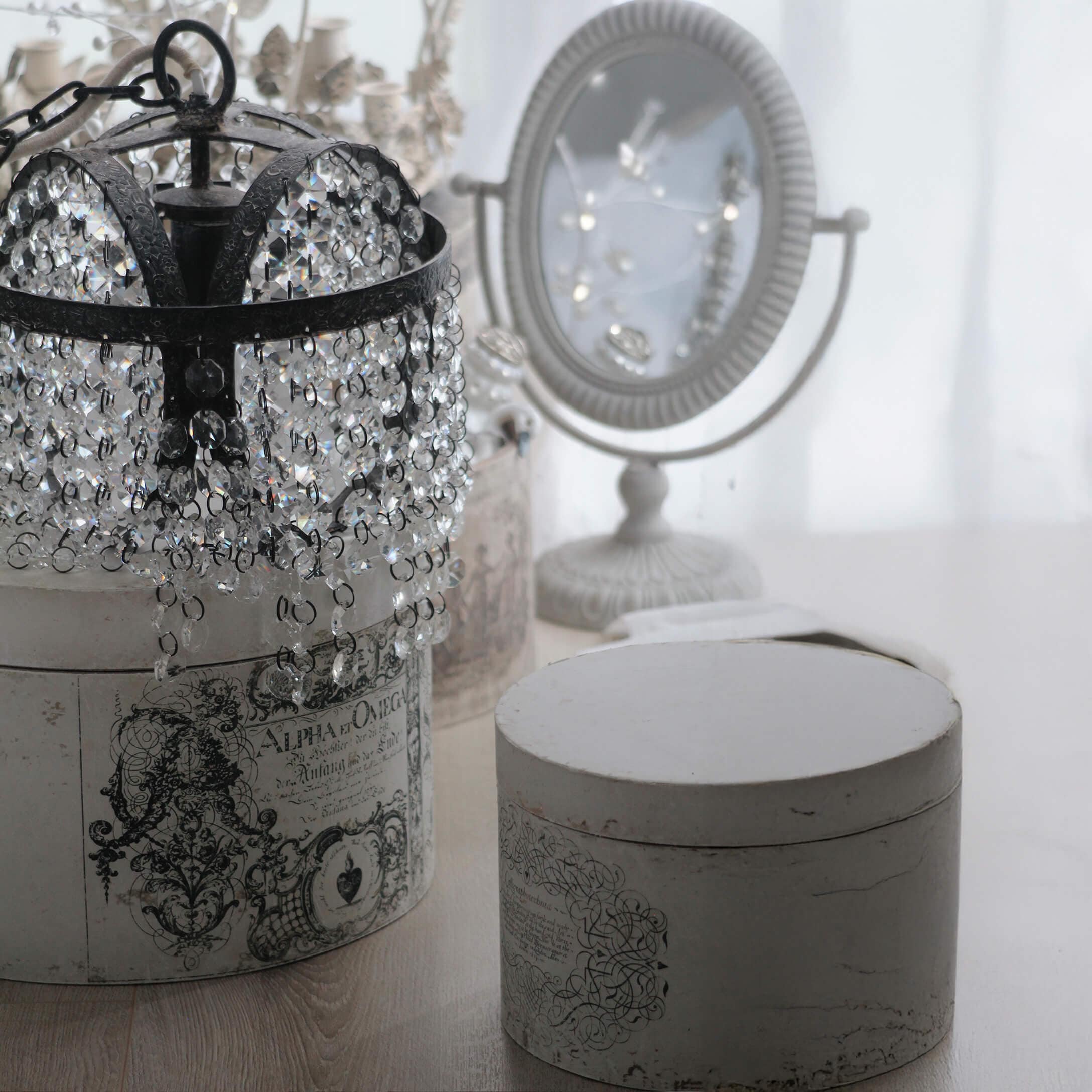 Kristallen kroonluchter met zwart metalen frame op witte vintage doos met ornamenten