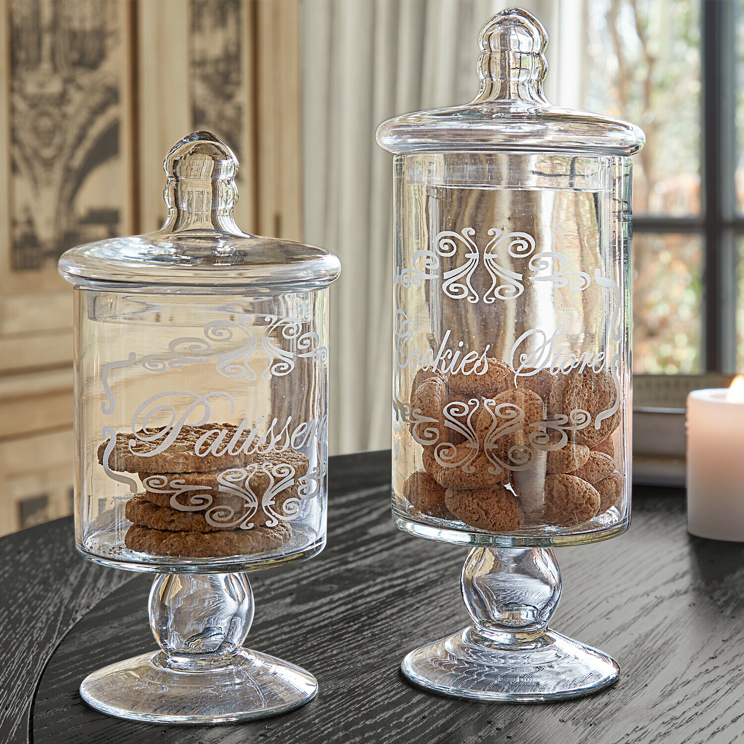 Pot set van 2 Suzie Glazen koekpotten met deksels en decoratieve tekst op een zwarte tafel