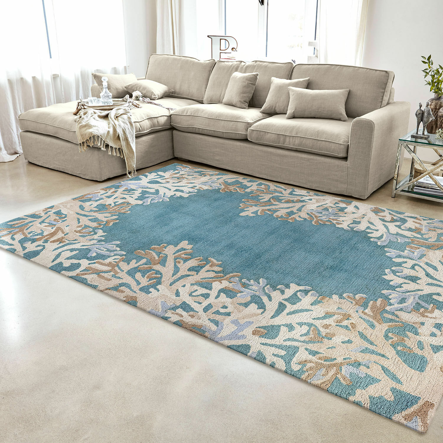 Blauw-beige vloerkleed met koraalpatroon in moderne woonkamer met beige bank en glazen tafel