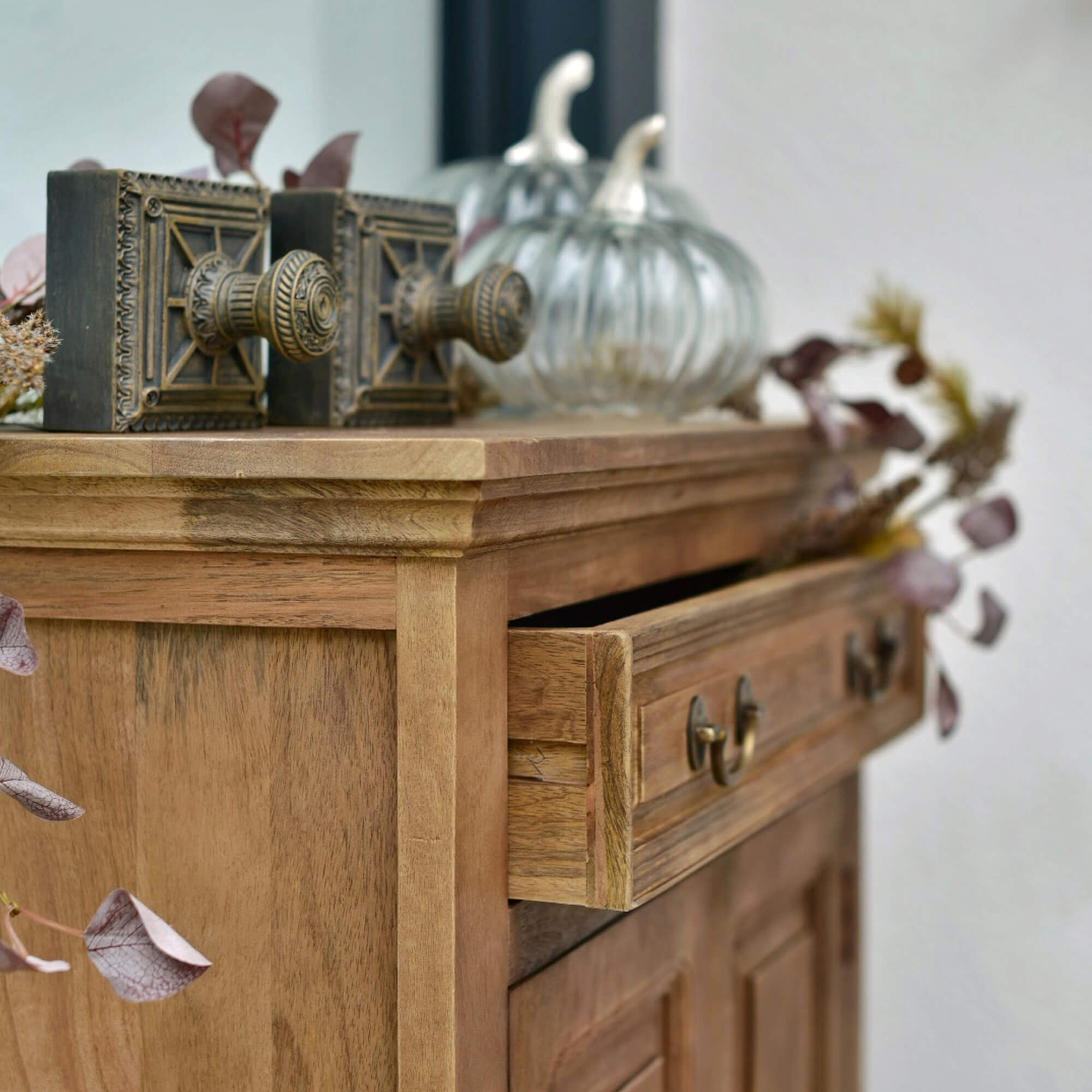 Houten kast met open lade, decoratieve messing knoppen en glazen pompoenversieringen