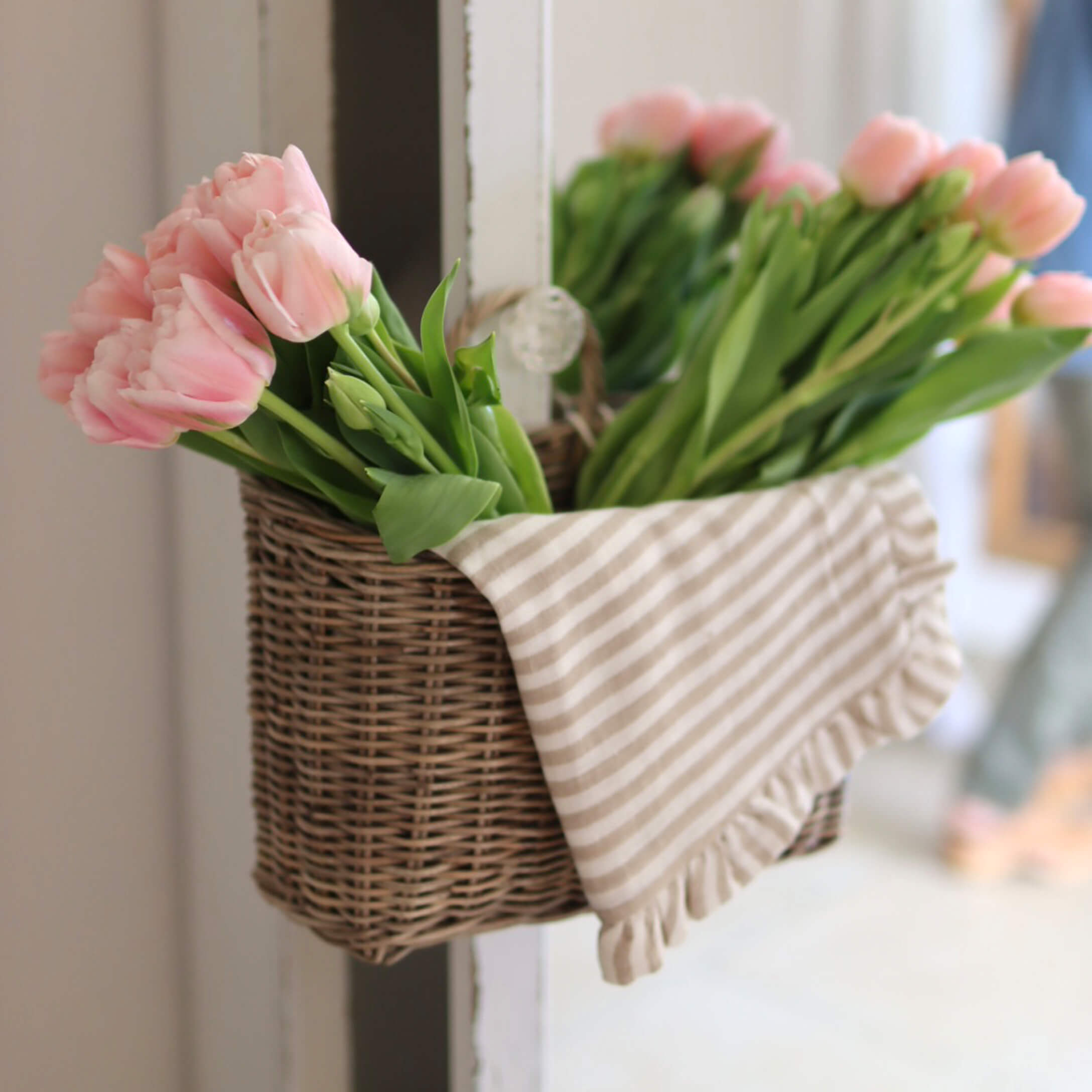 Rieten mand met roze tulpen en gestreept katoenen doek voor interieurdecoratie