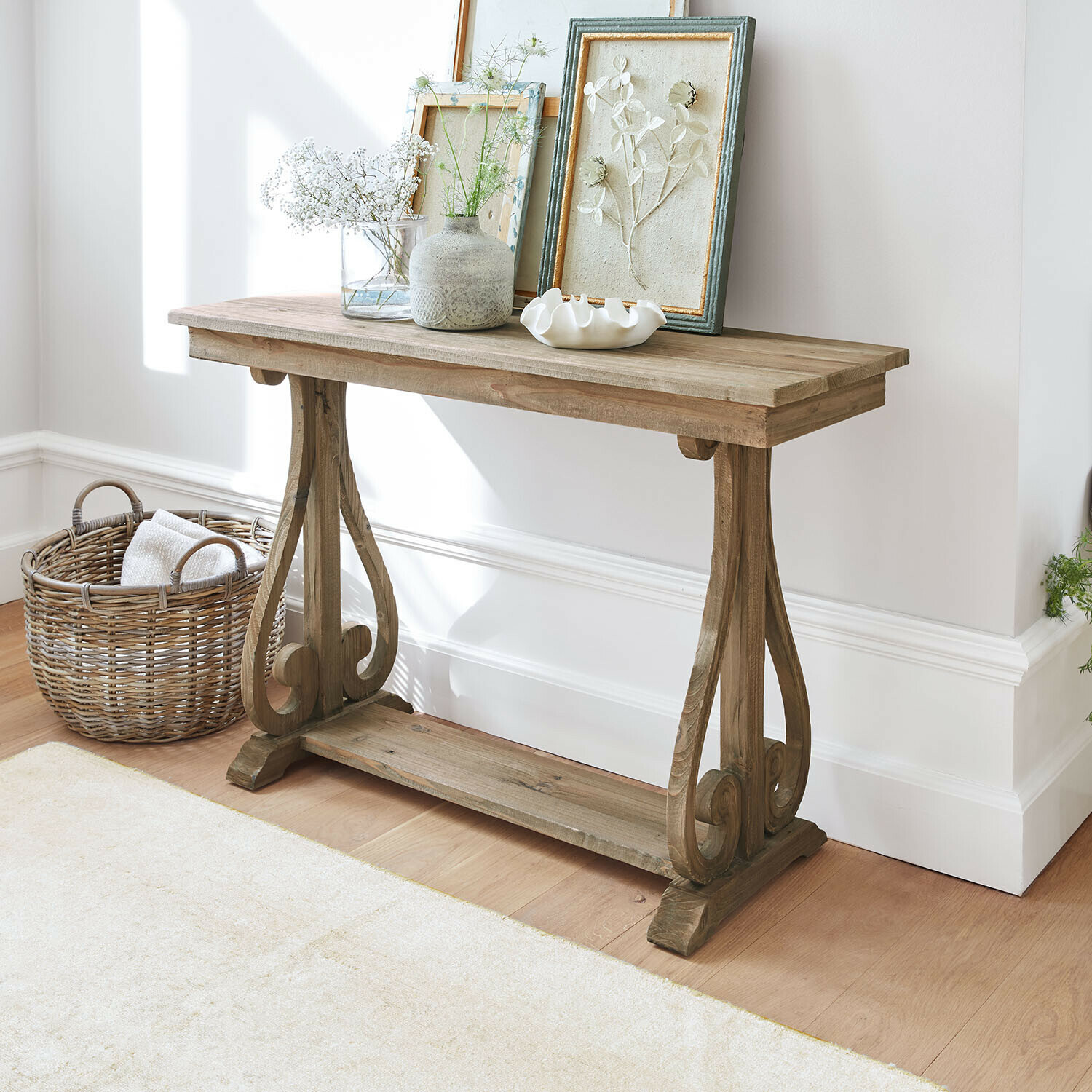 Houten sidetable in natuurlijke kleur met decoratieve lijsten en vazen in lichte ruimte