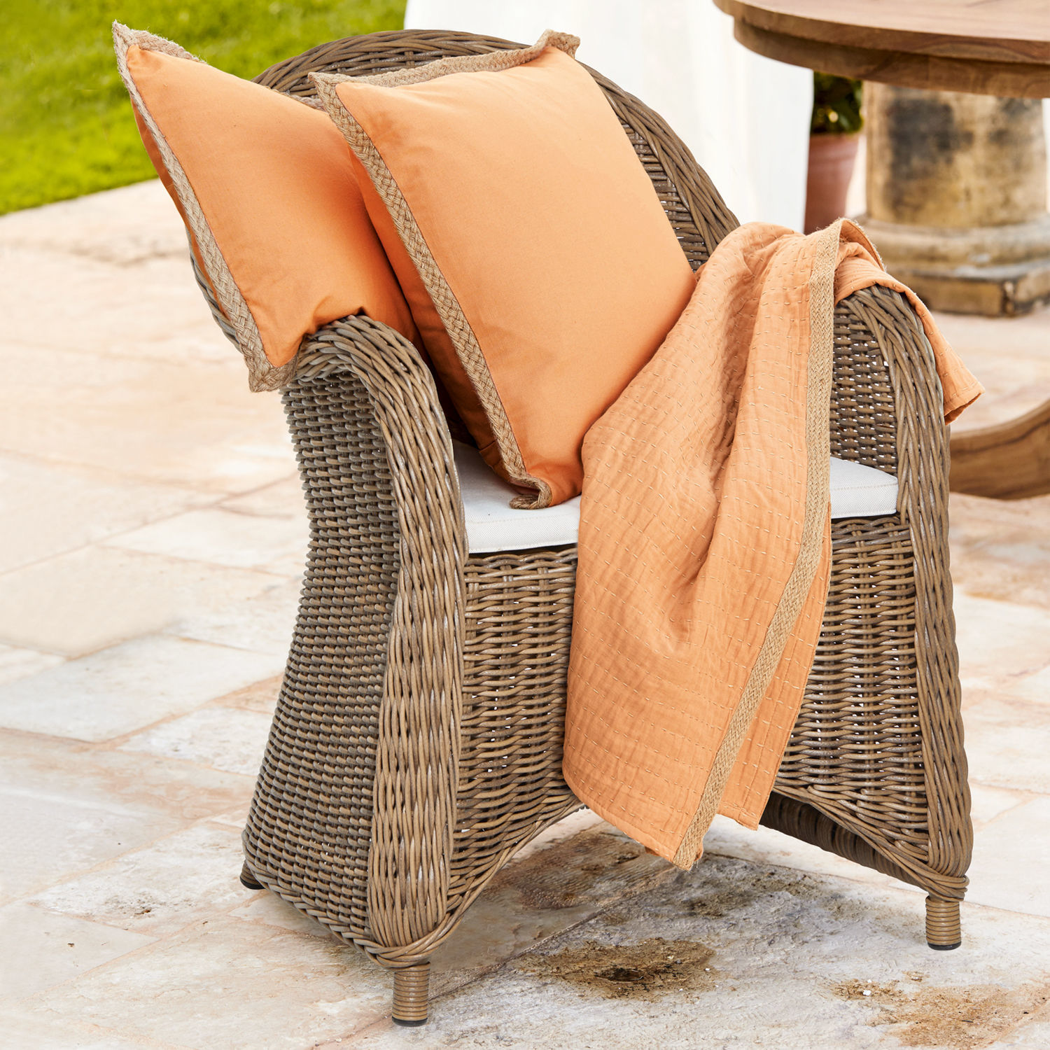 Stoel Kerun Rotan stoel met oranje kussens en deken voor terras of tuin