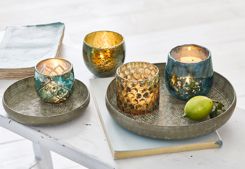 Metalen oosterse schalen met gouden en turquoise decoratieve kaarsenhouders op witte tafel