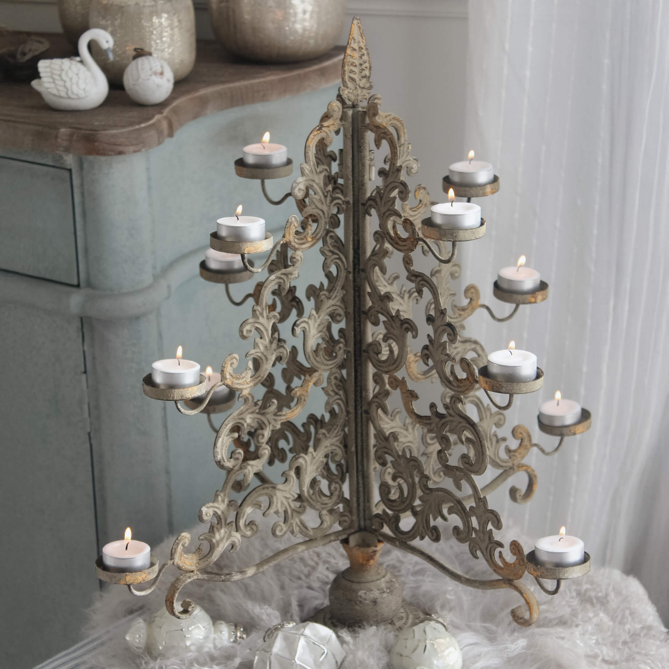 Metalen kandelaar met geornamenteerd patroon in antiek goud met brandende theelichtjes