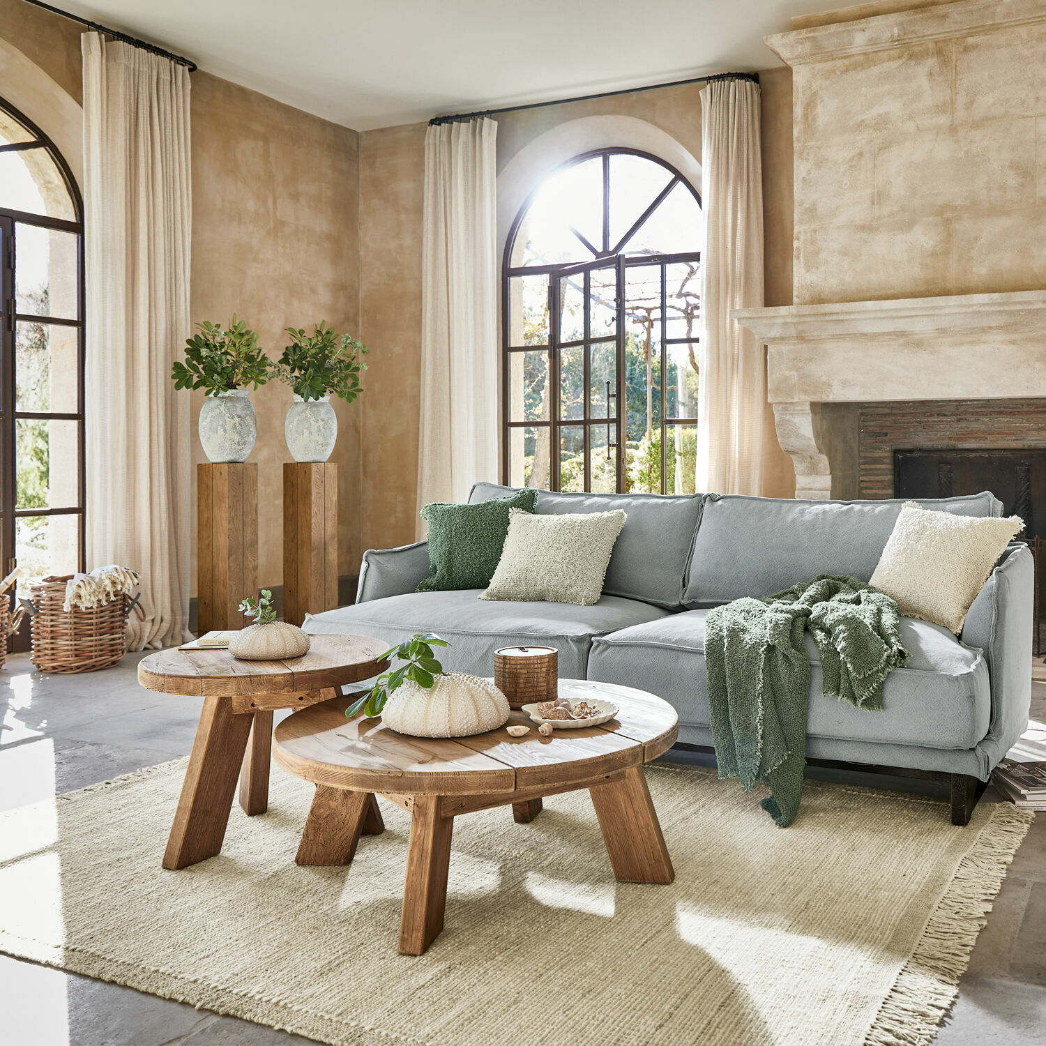 Gezellige woonkamer met grijze bank, houten salontafels en lichte natuurlijke vloerkleed