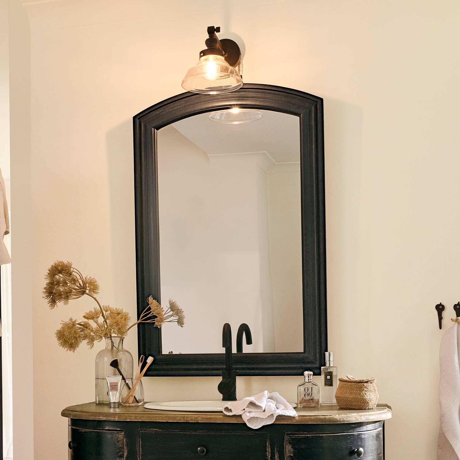 Zwarte houten spiegel met lijst boven wastafel met zwarte kraan en badkamerdecoratie