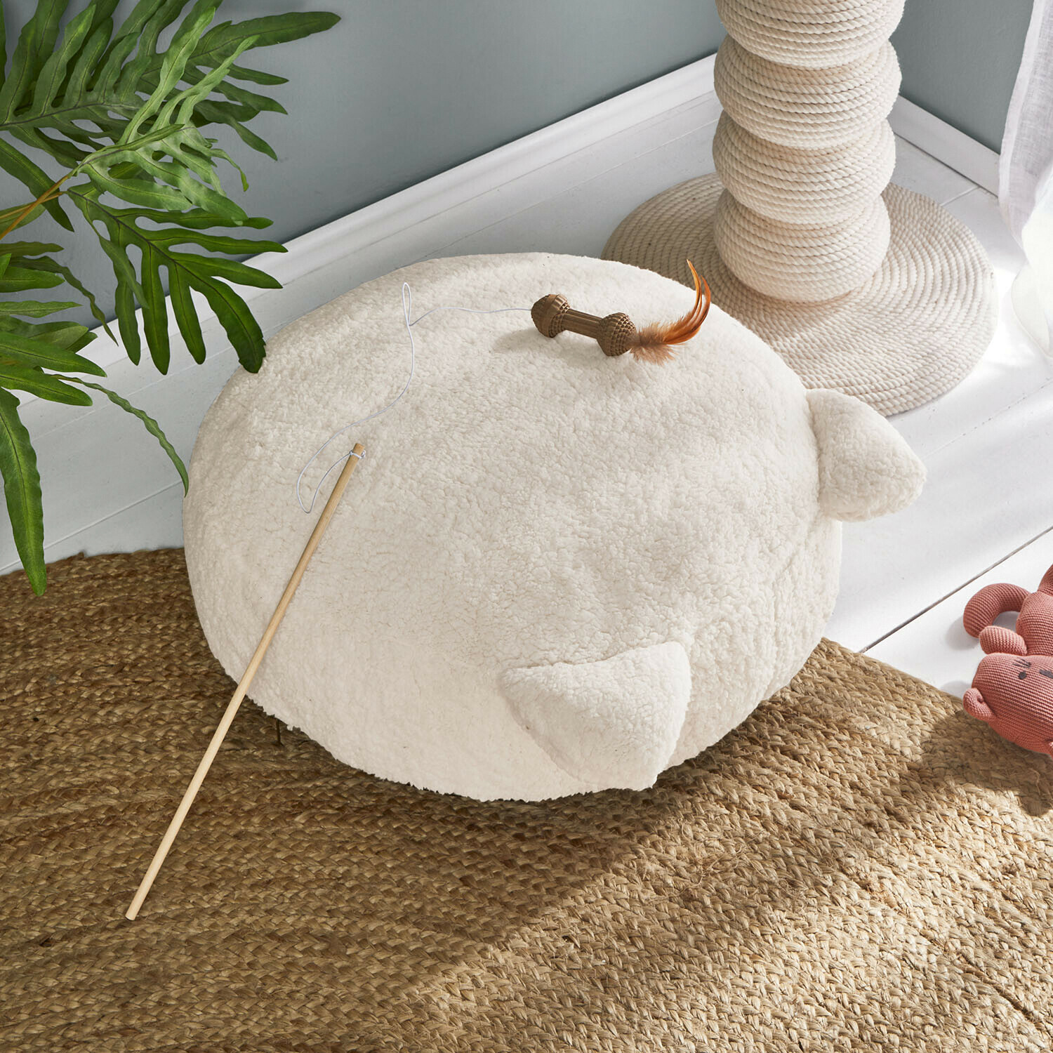 Ronde crèmekleurige kussen van zacht materiaal met oren, kattenspeelgoed met stok en veer