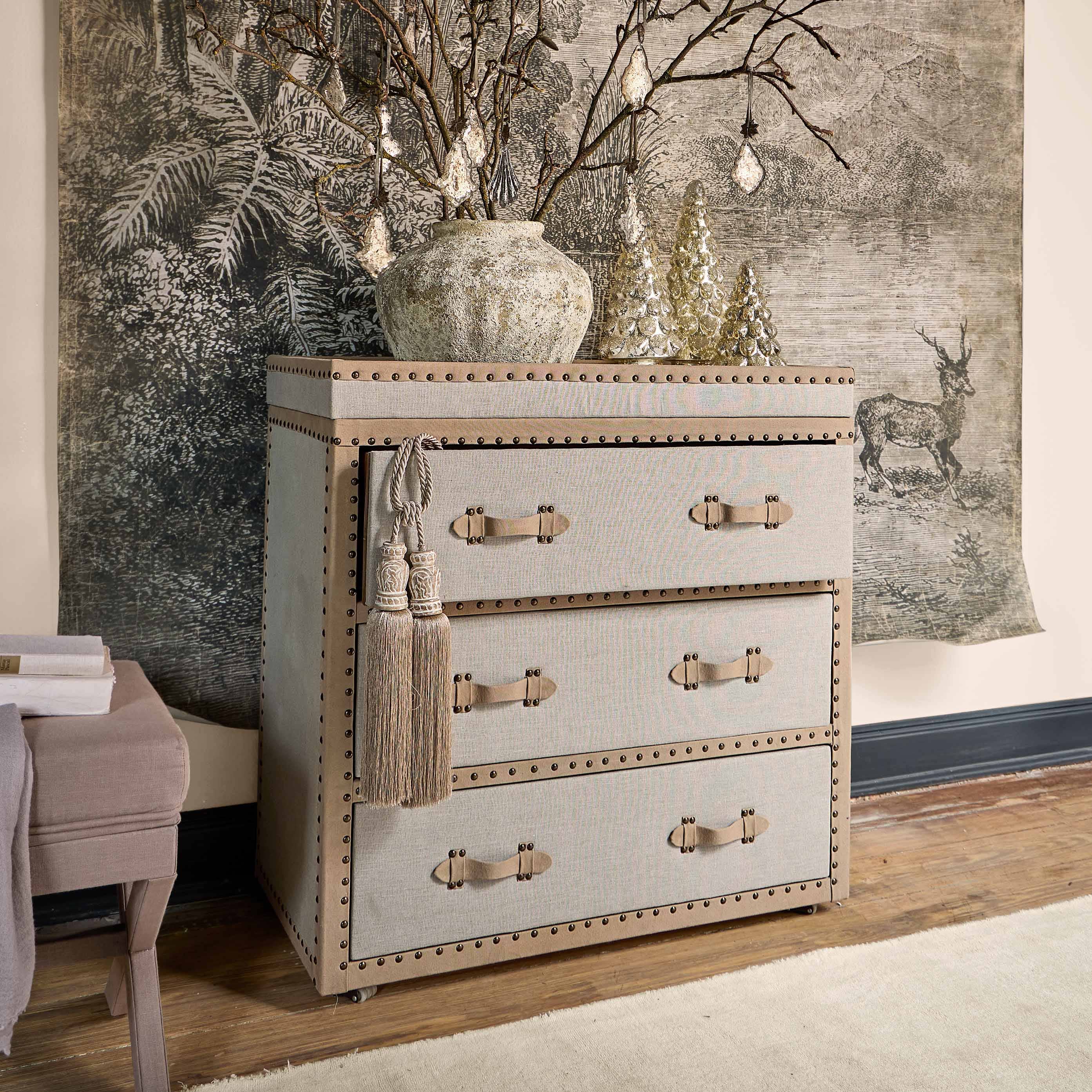 Beige stoffen ladekast met decoratieve handgrepen en kwasten, vintage stijl voor woonkamer