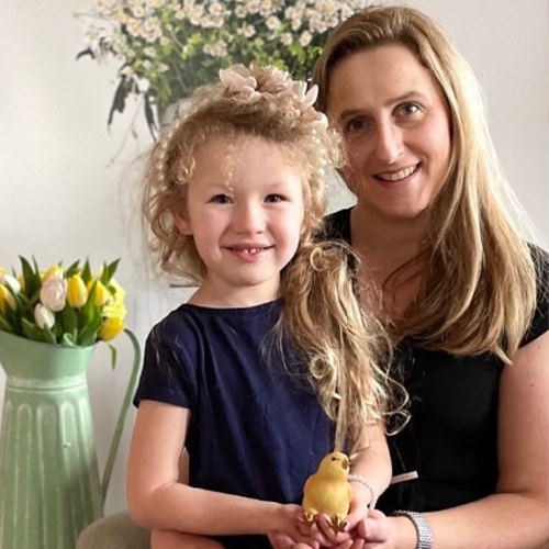 Lachende vrouw en meisje met vogeldecoratie in lichte kamer met bloemen
