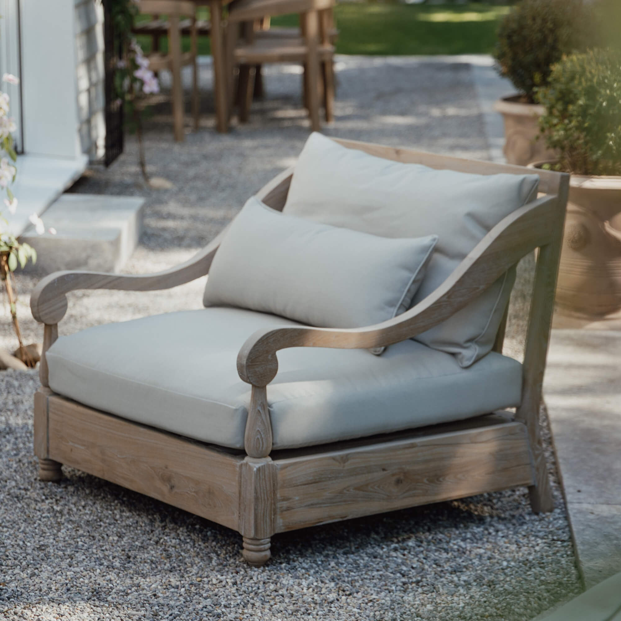 Tuinbank van licht hout met crèmekleurige kussens, comfortabel terrasmeubilair