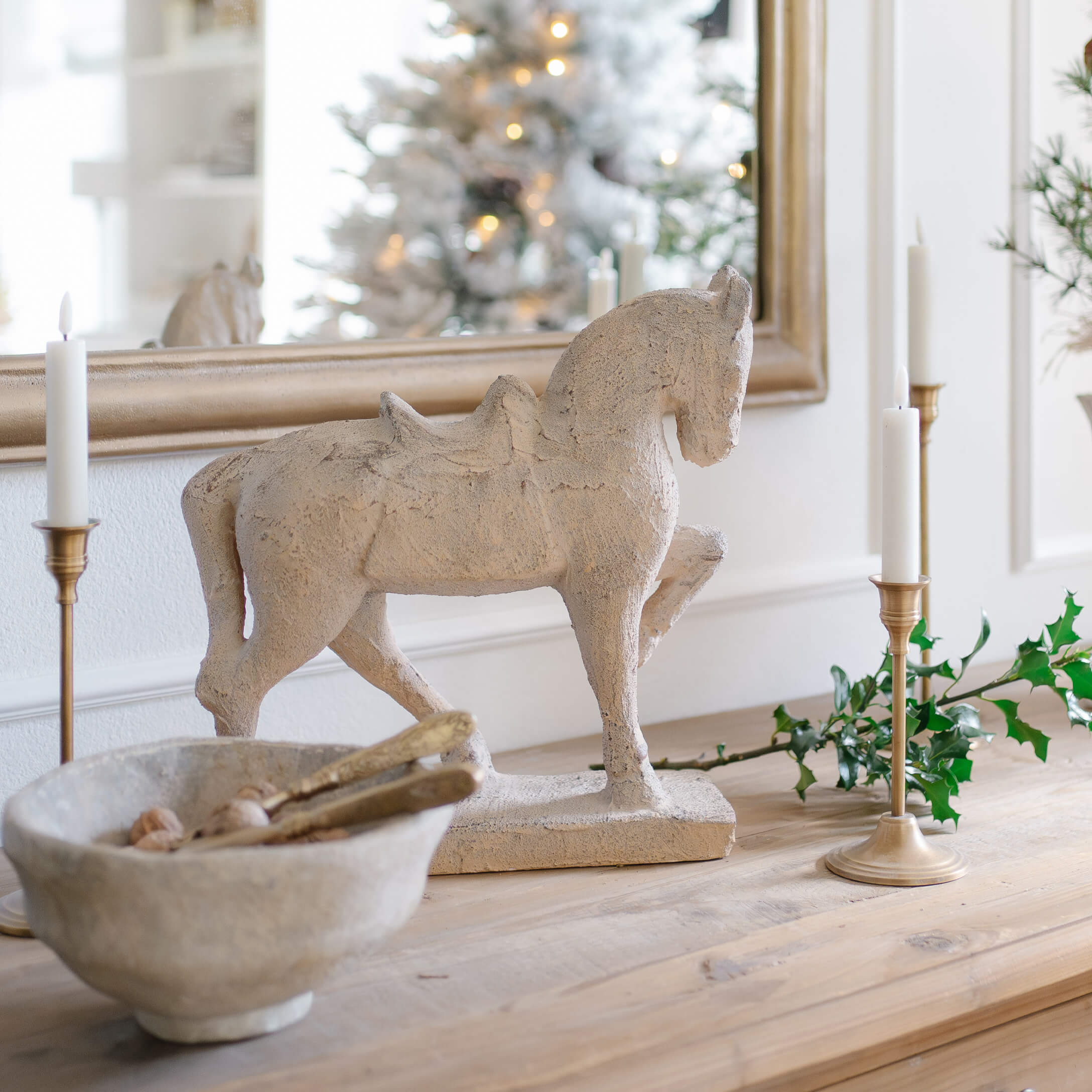 Decoratief paardenbeeld van steenachtig materiaal in beige op houten tafel met kaarsen