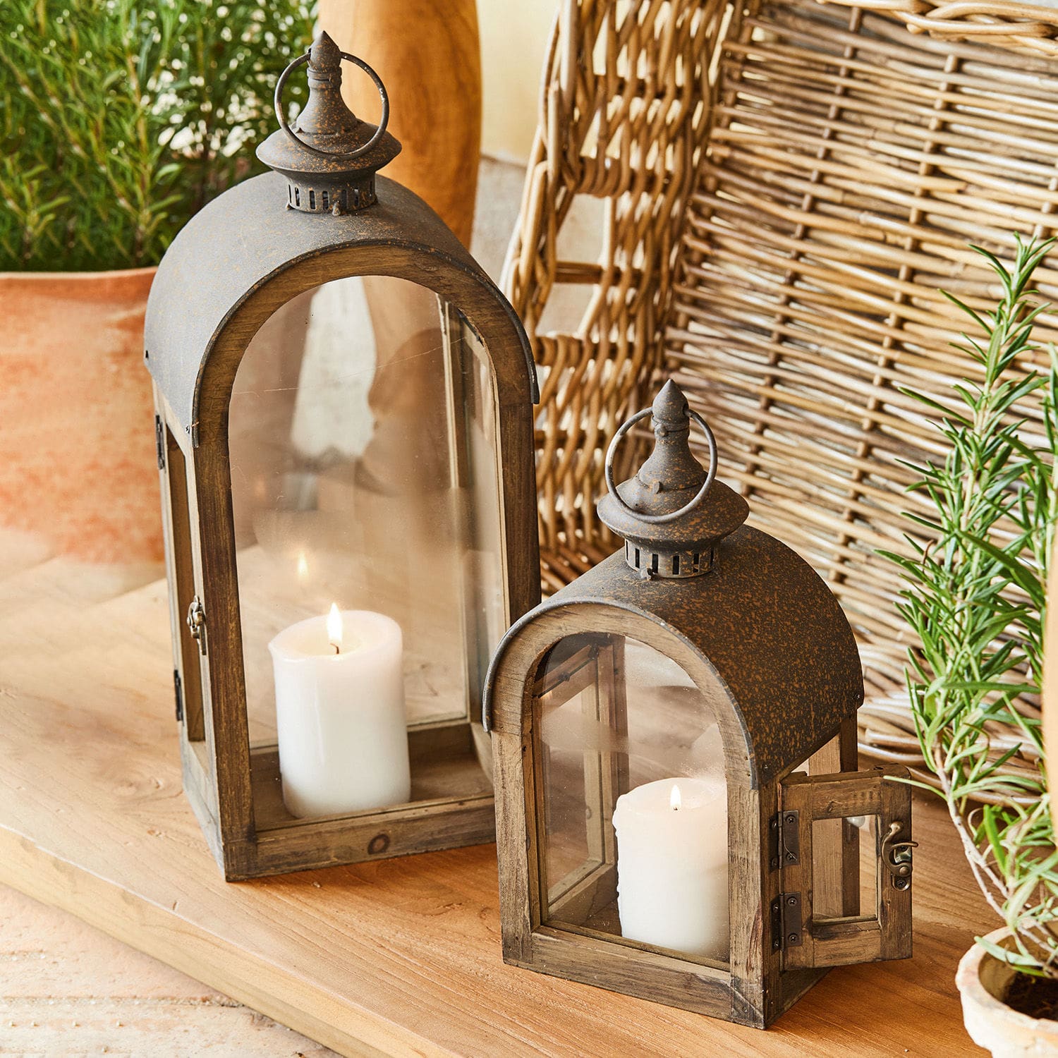 Houten lantaarns met roestige metalen deksel en witte kaarsen op houten tafel, rustieke decoratie