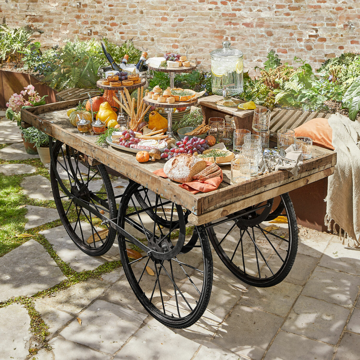 Serveerwagen Annabel Tuin tafel van hout en metaal met wielen, versierd met snacks en drankjes buiten