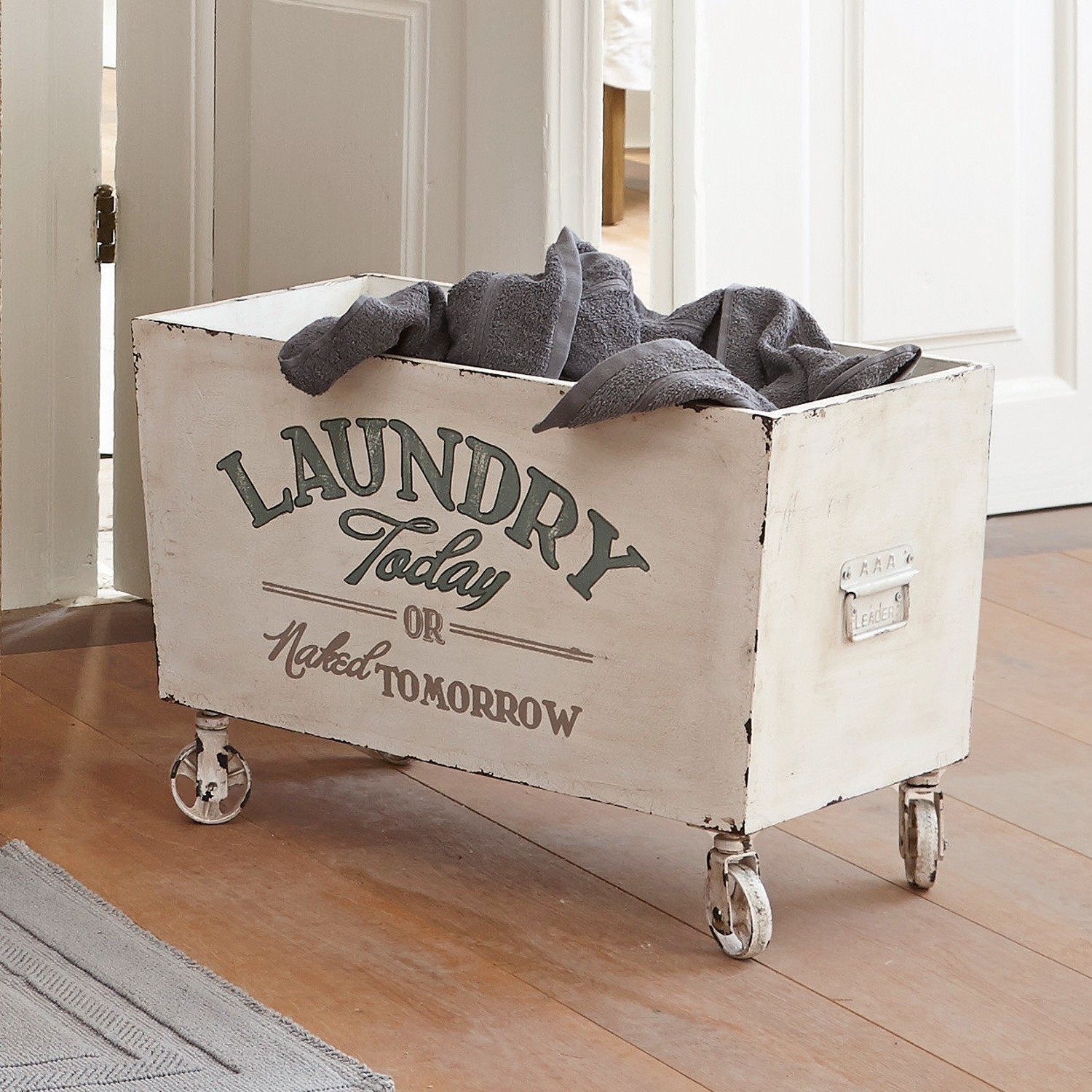Houten kist Today Witte metalen wasmand op wieltjes met grijze handdoeken in houten interieur