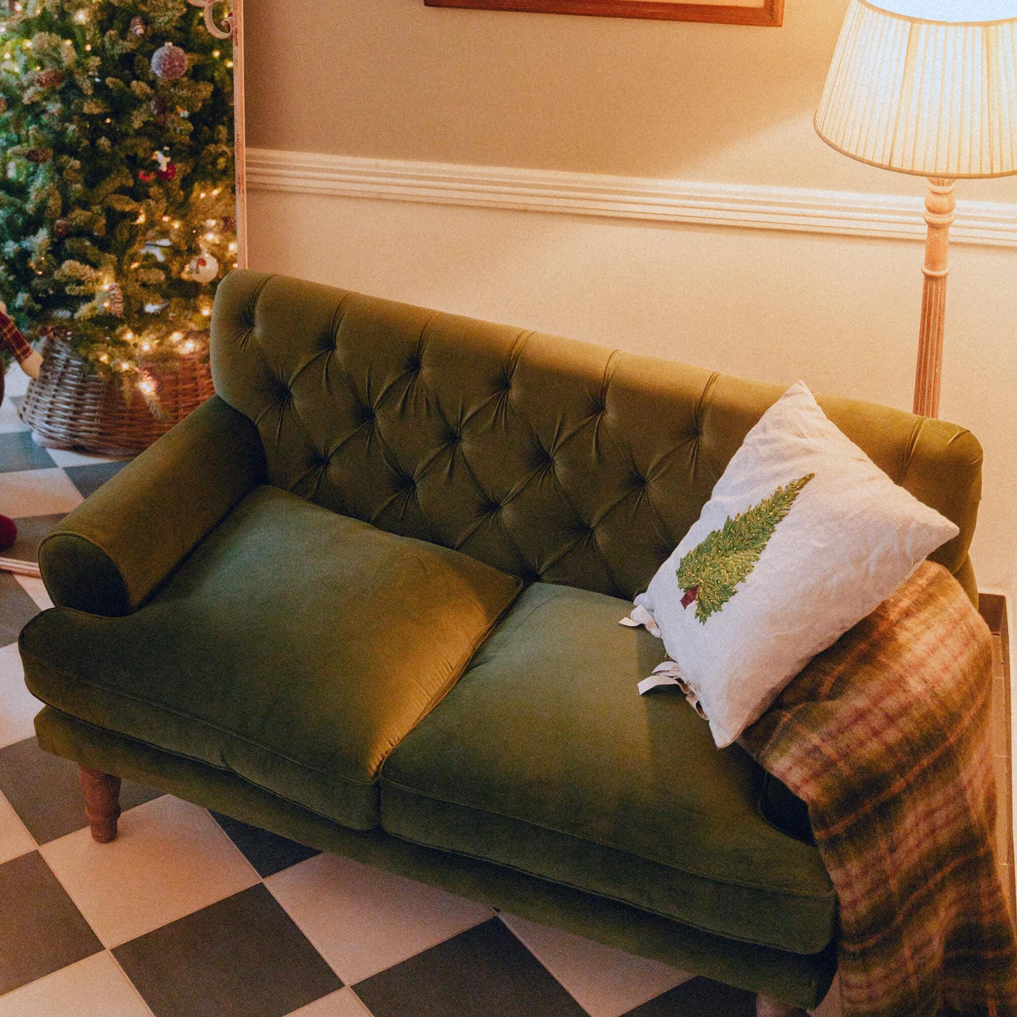 Groene fluwelen bank met gestikte rugleuning en kerstboomkussen in gezellige kamer