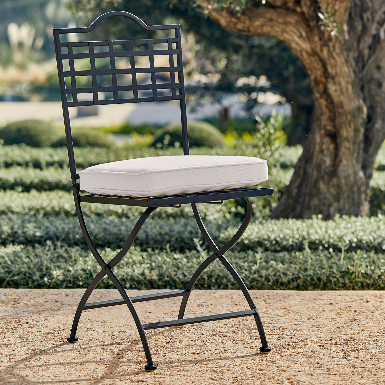 Zwarte metalen tuinstoel met wit zitkussen, ideaal voor stijlvolle buitenmeubels