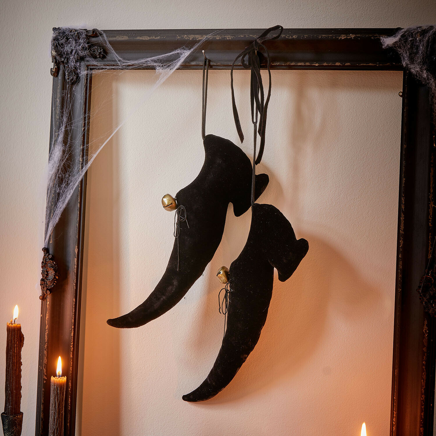 Decoratieve schoen set van 2 Trésalya Zwarte fluwelen heksenlaarzen met belletjes hangend aan een oude lijst met spinnenwebben en kaarsen