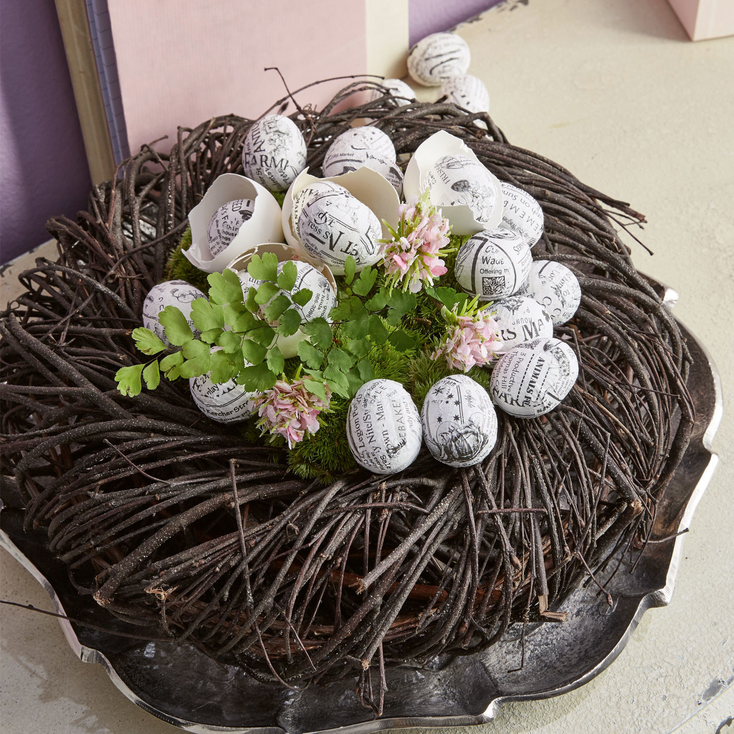 Decoratieve krans van takken met witte eieren met zwarte print en groene bladeren als decoratie