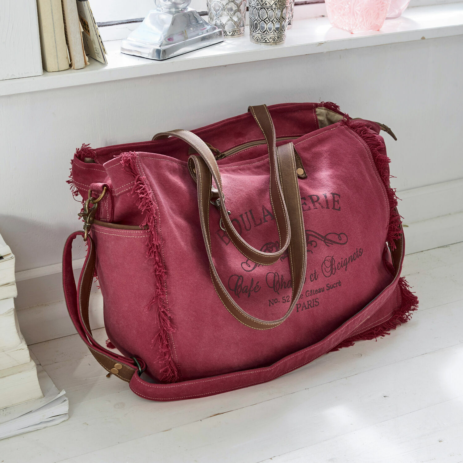 Tas Anoush Reistas van rood canvas met bruine handvatten en vintage opdruk op witte vloer