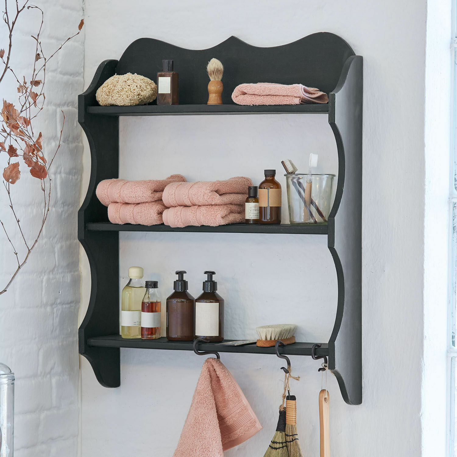Zwart houten badkamerrek met roze handdoeken en verzorgingsaccessoires