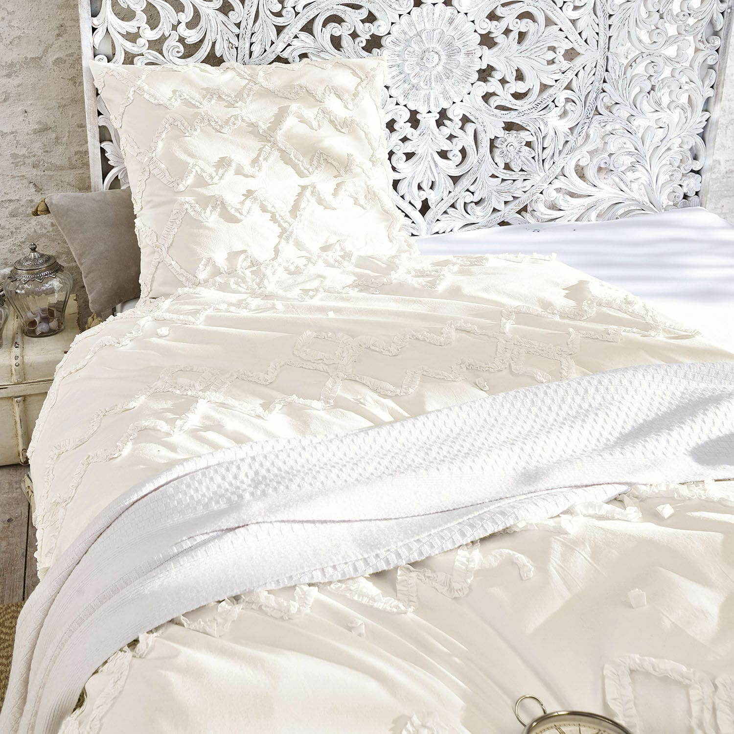 Beddengoed Élaine Crèmekleurig katoenen beddengoed met decoratief patroon en zachte witte deken op vintage bed