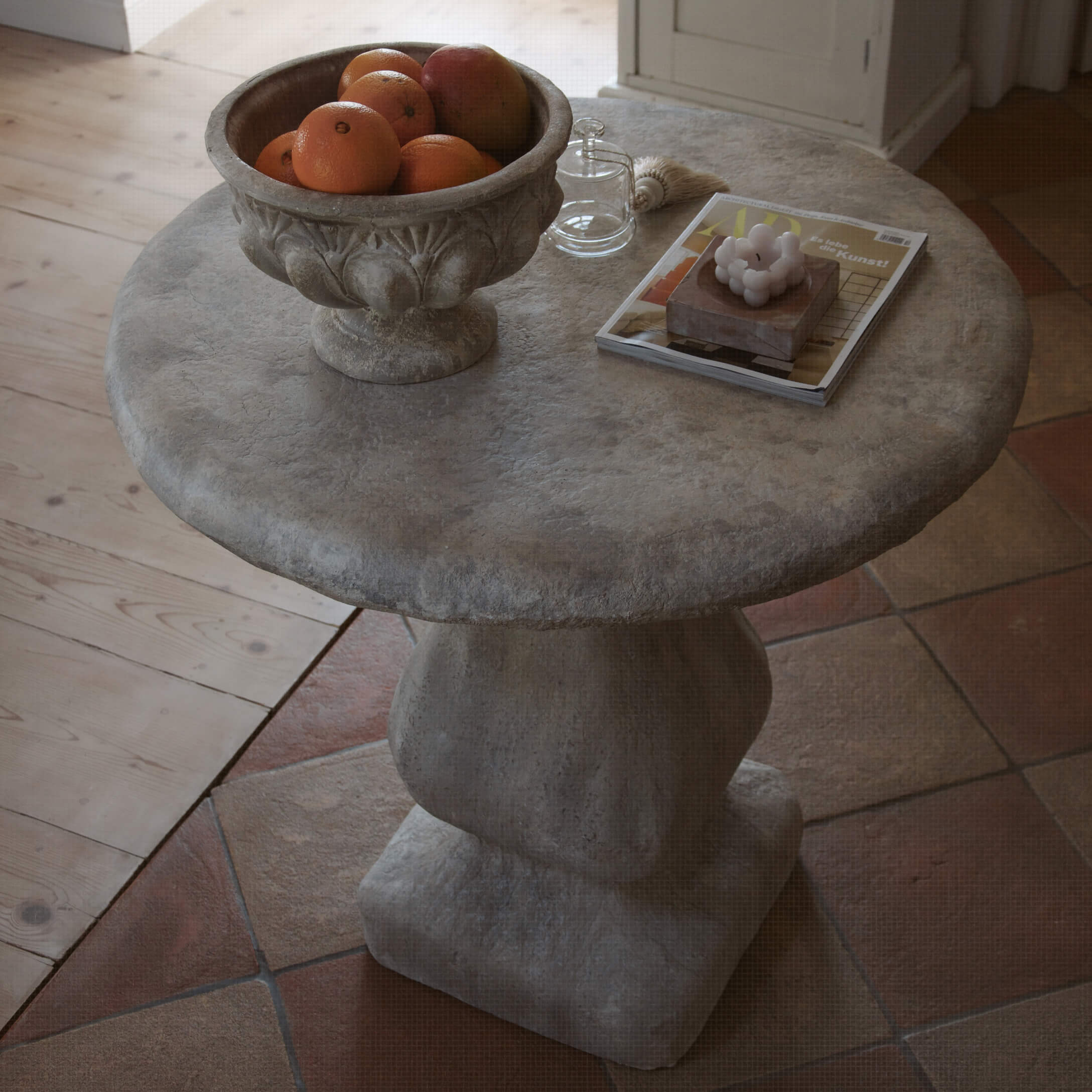 Ronde grijze stenen tafel met fruitschaal en decoratieve voorwerpen op het blad