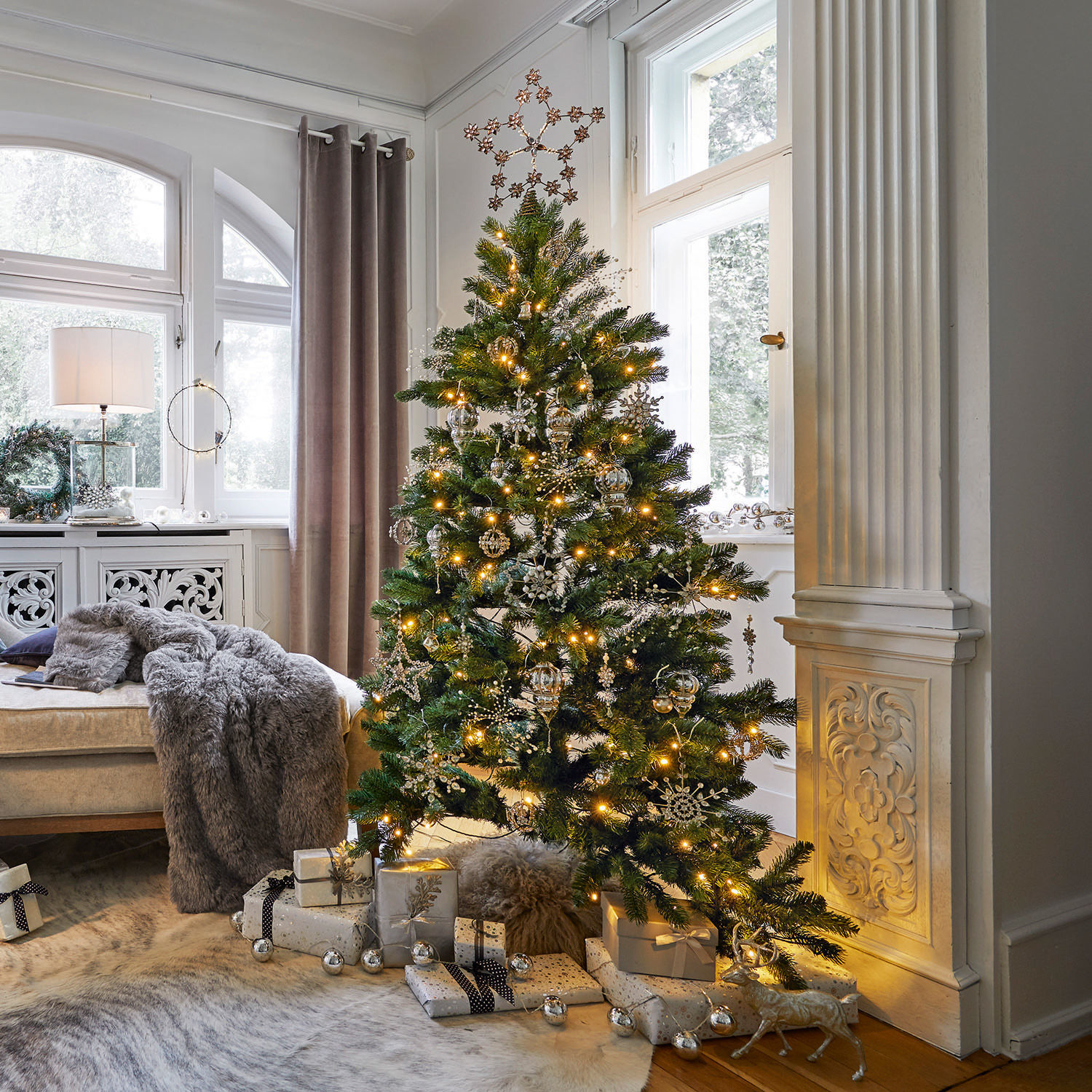 Kerstboom Helford Kerstboom met groene takken en gouden versieringen in lichte woonkamer met cadeaus eronder