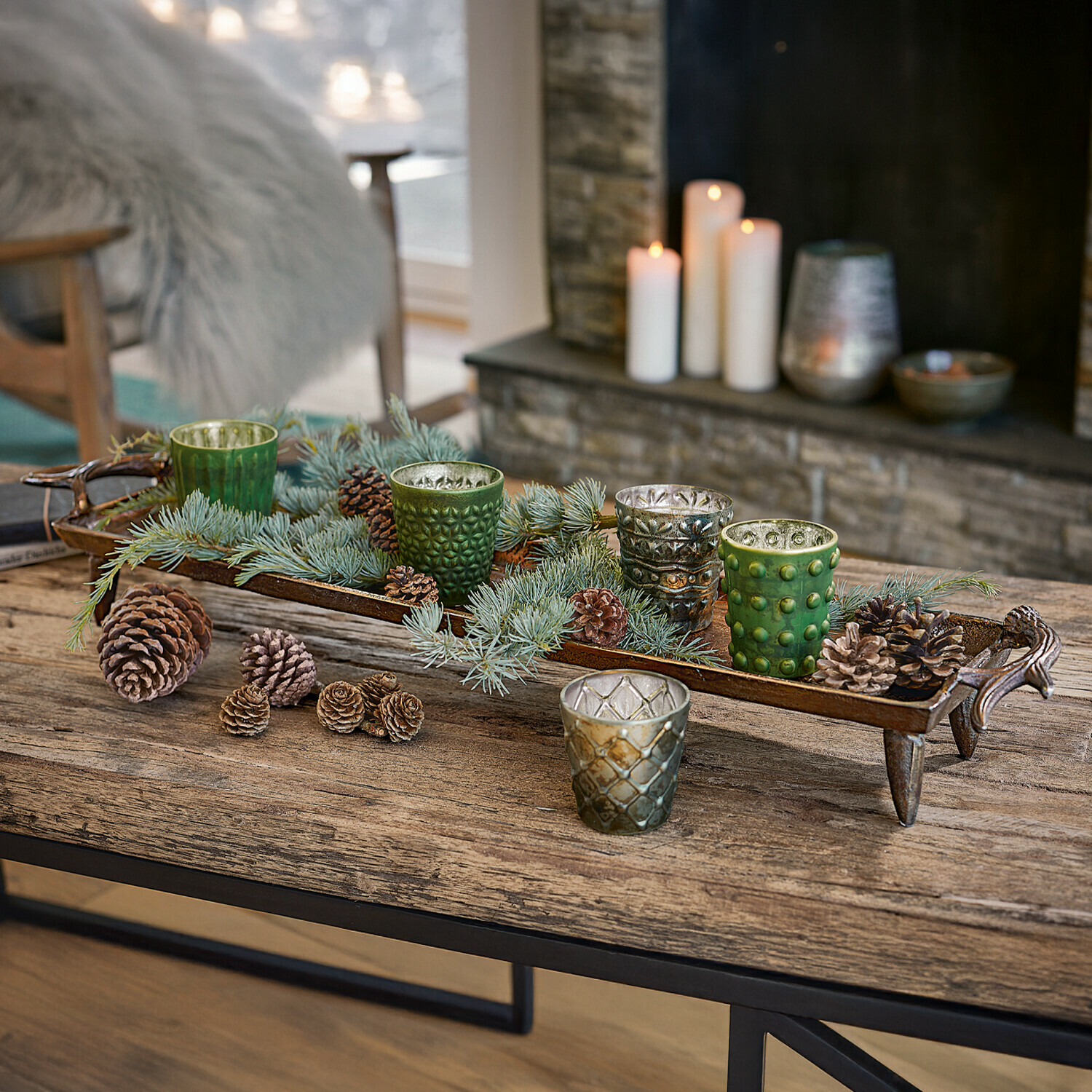 Plateau Donia Decoratief metalen dienblad met groene en zilveren glazen theelichthouders en dennenappels op houten tafel